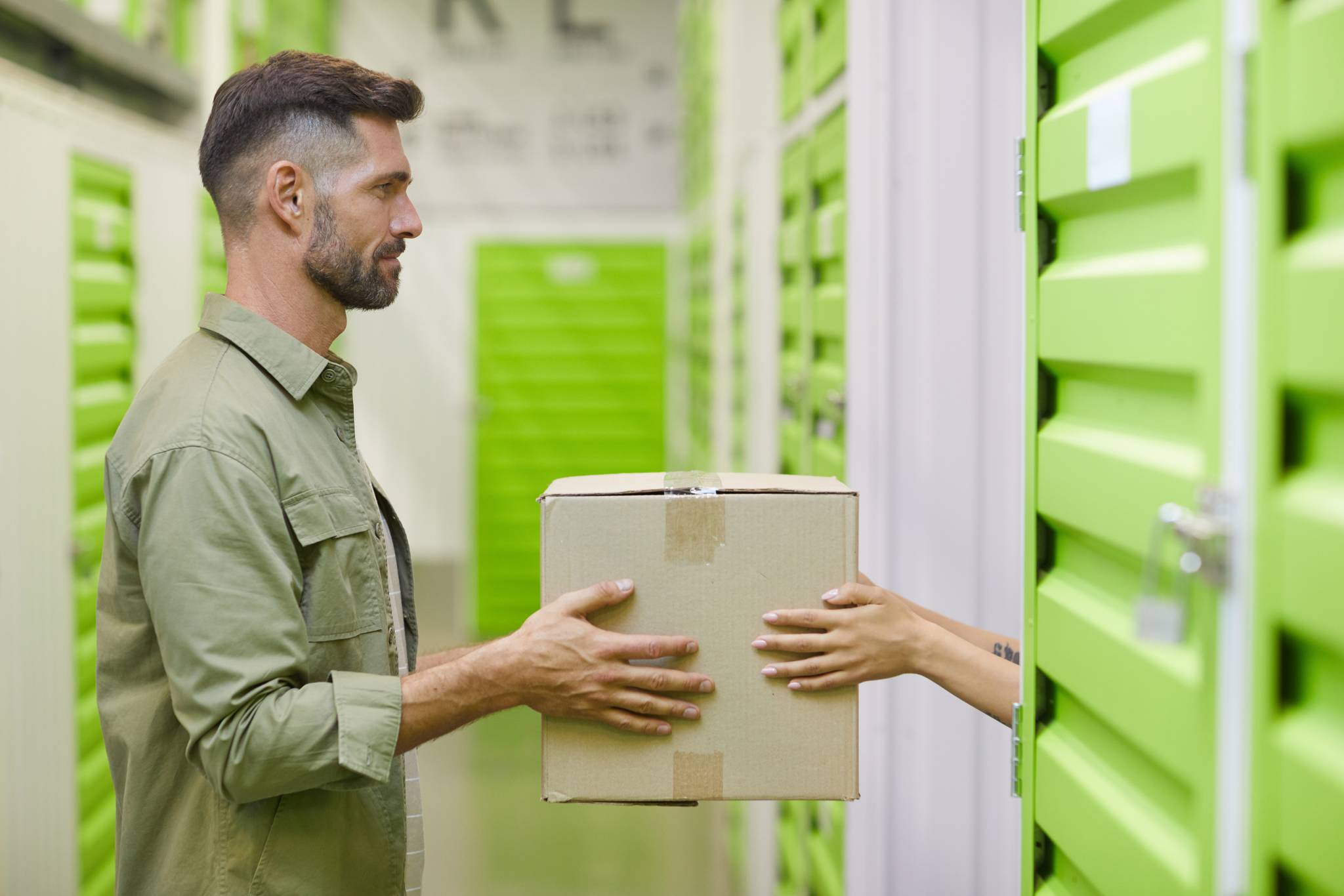 side view man passing box to other in storage unit