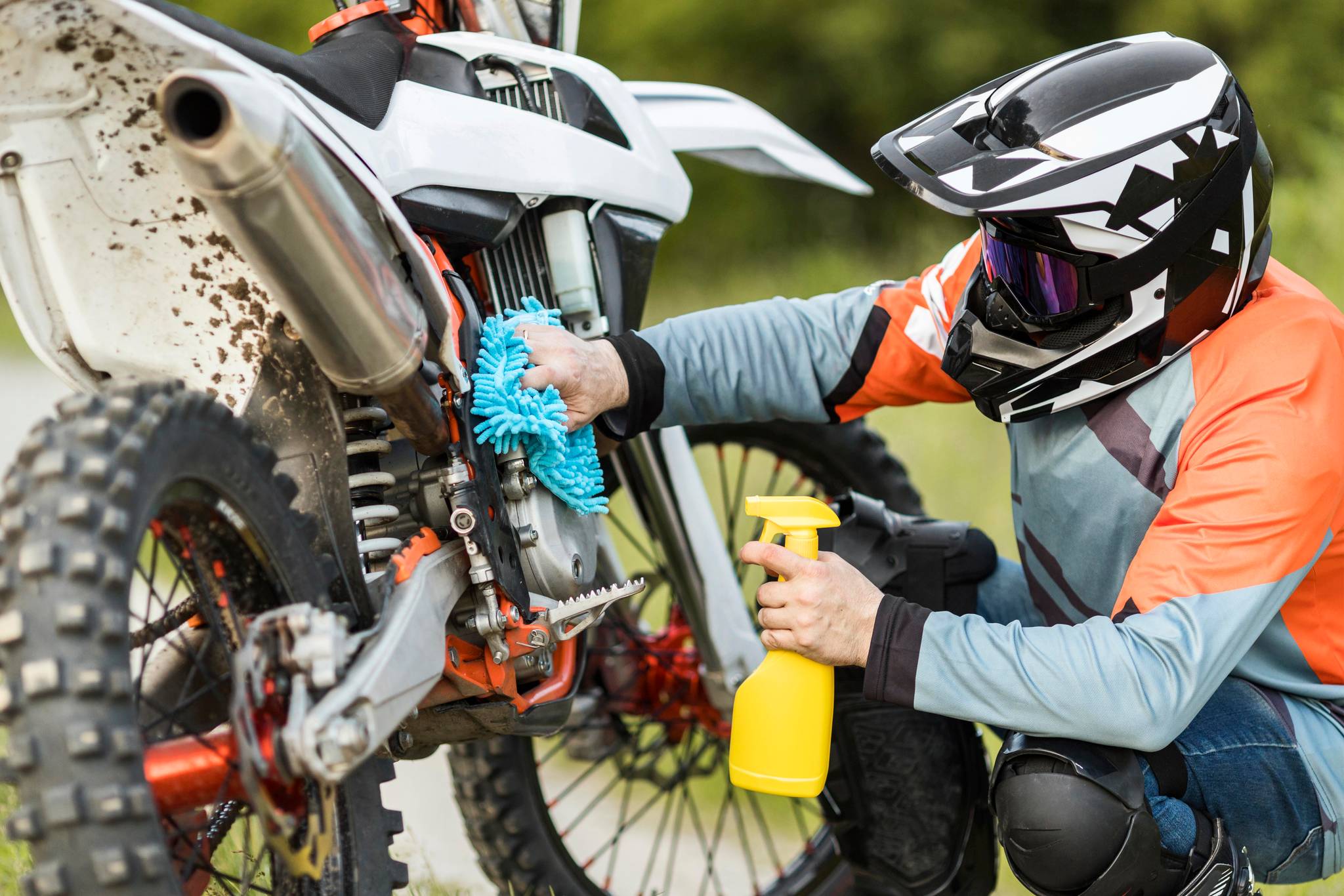 Man in helmet cleaning motorbike