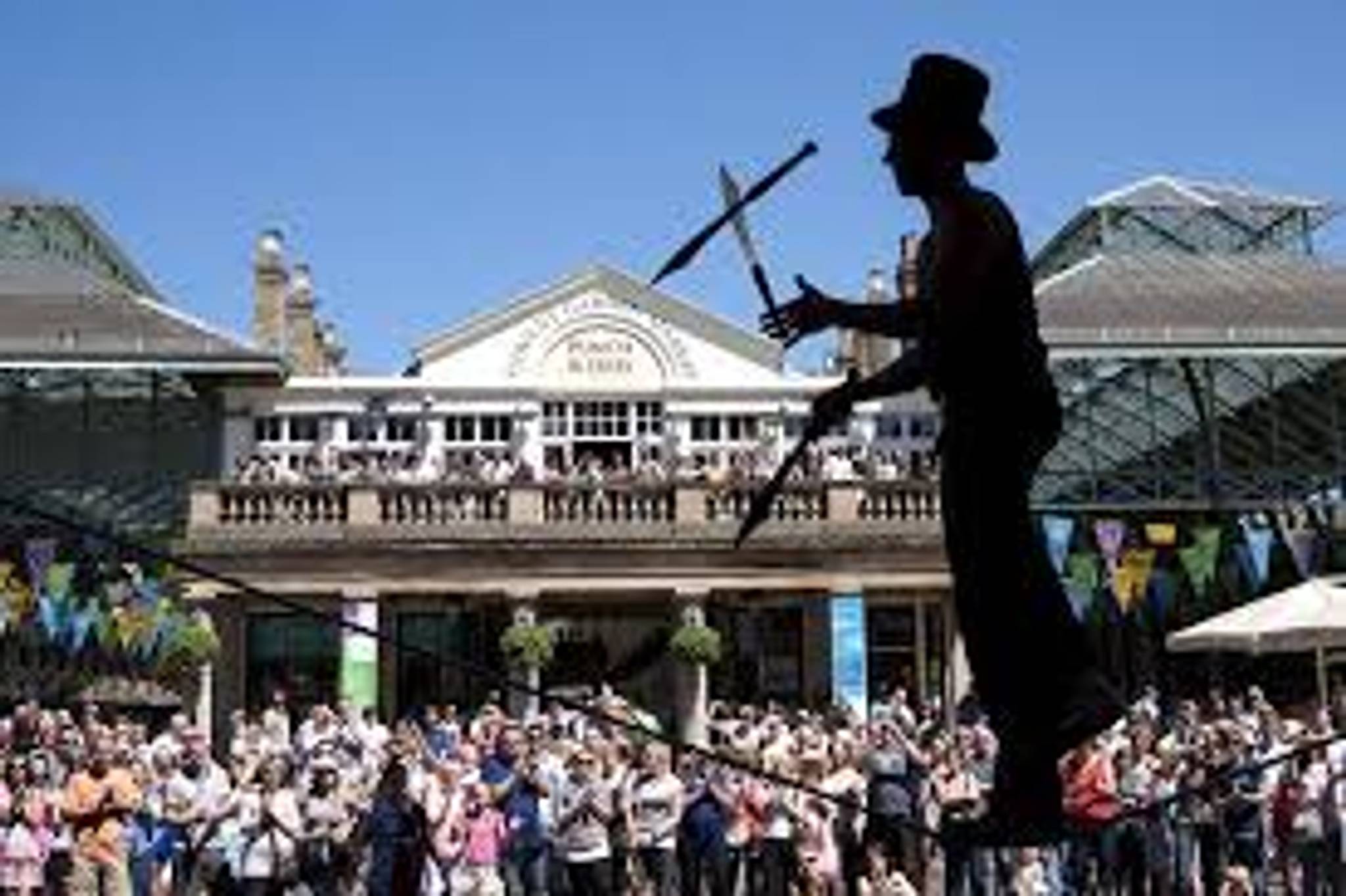 street performer juggling on unicycle with crowd at covent garden