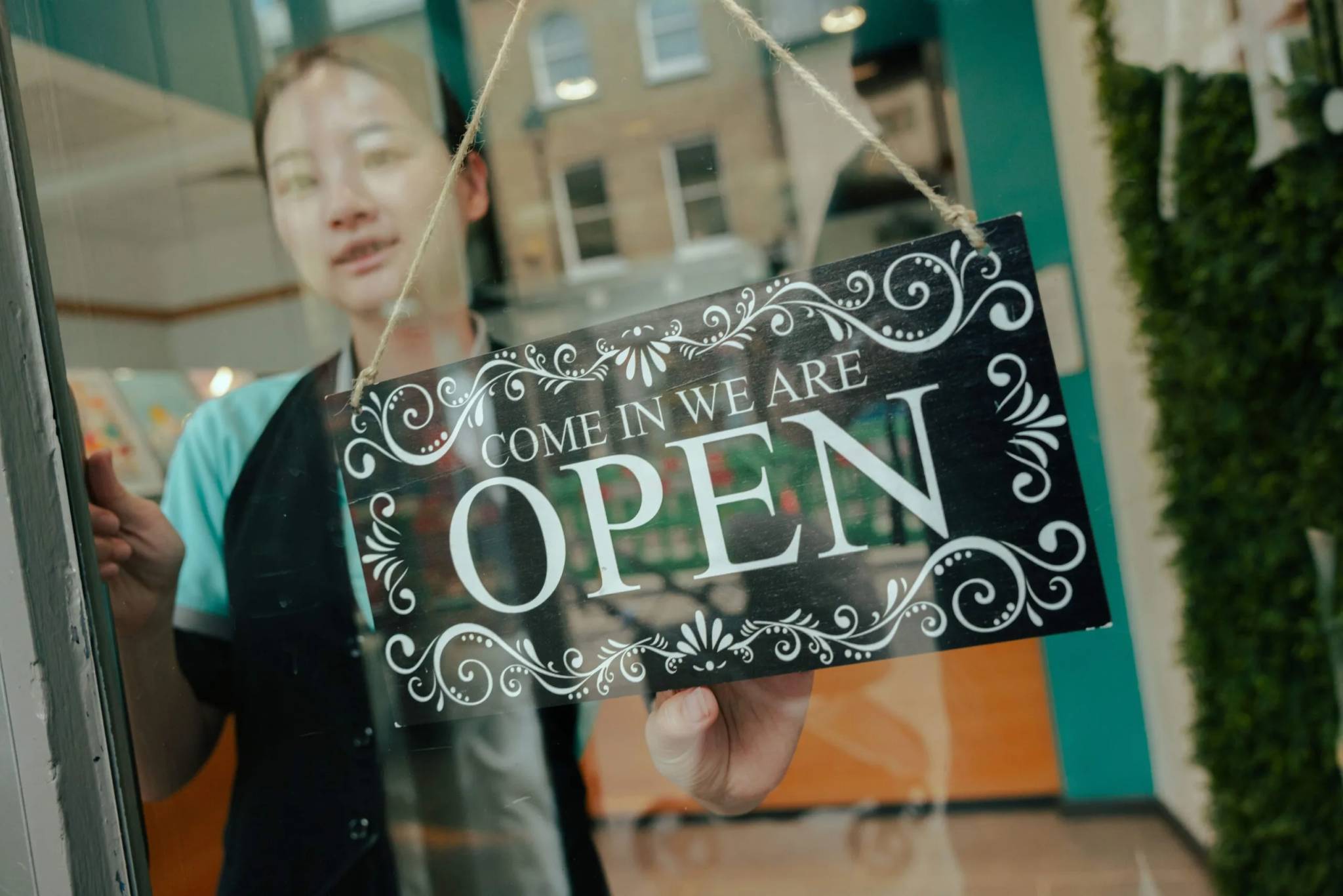 woman behind glass door open sign