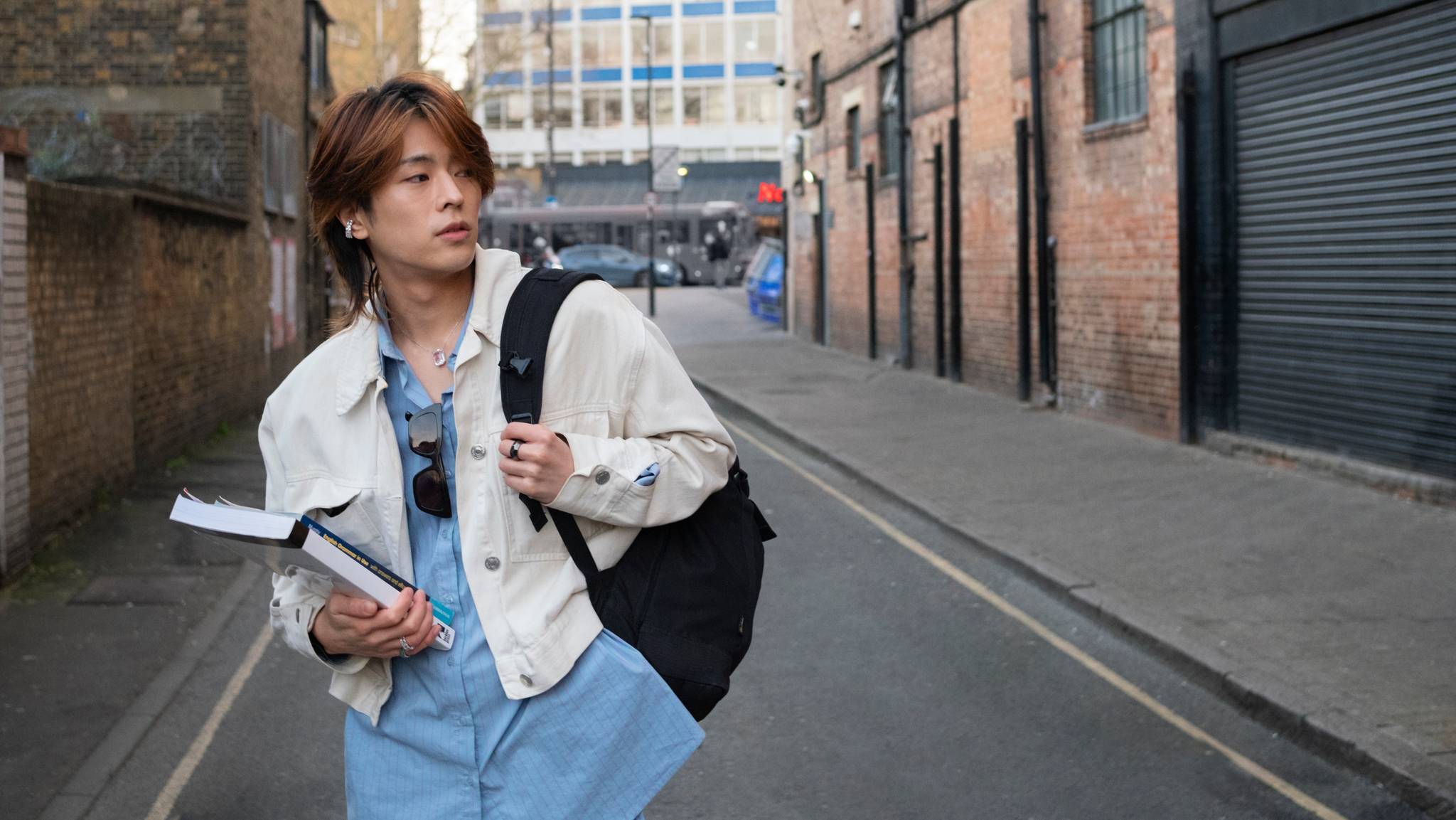 young adult with book on street