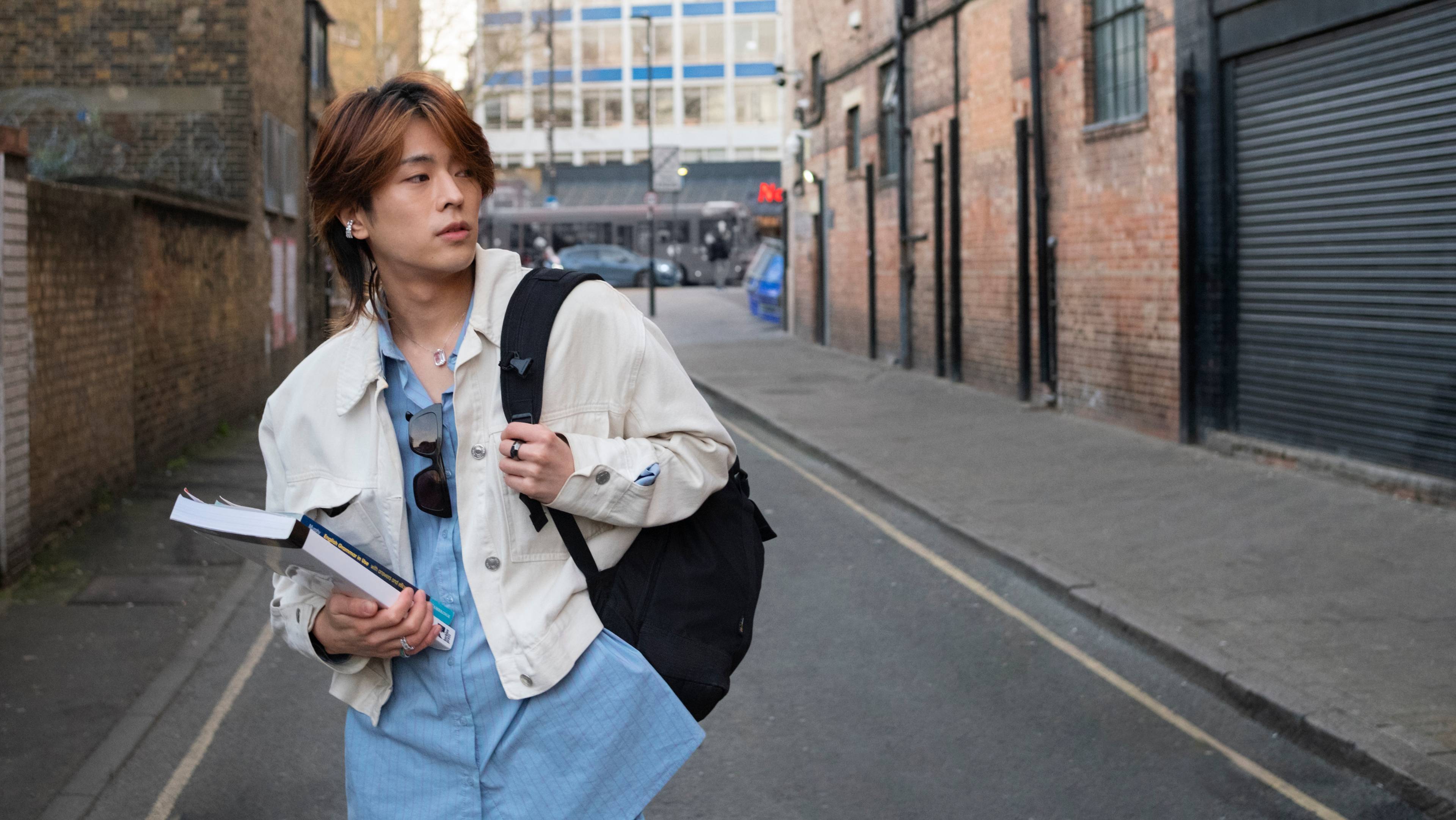 young adult with book on street