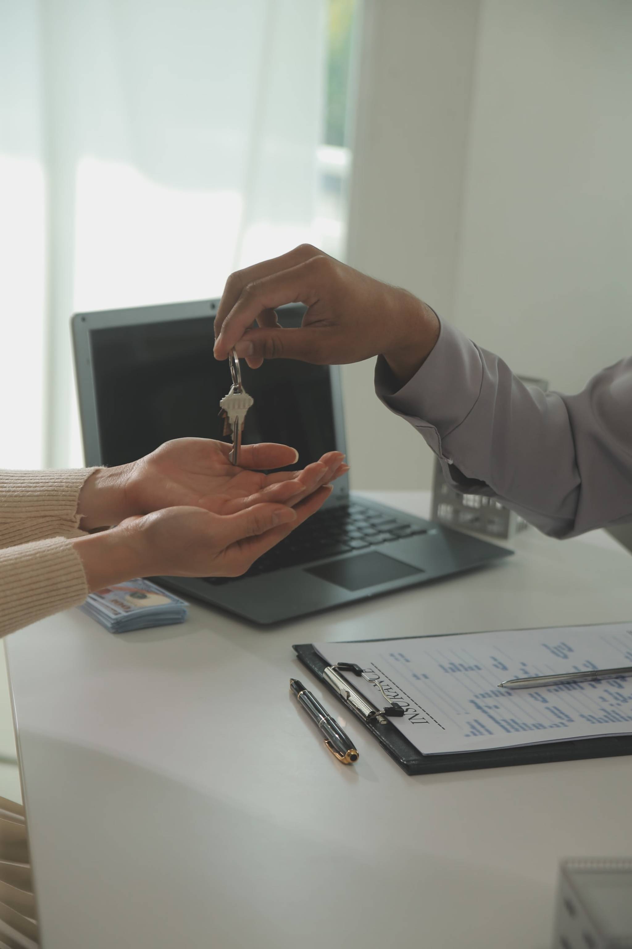 A real estate agent handing a set of keys to a woman.