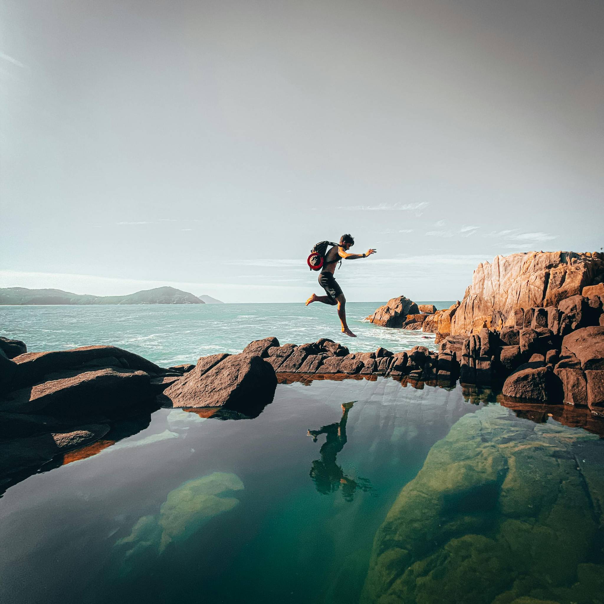 Man jumping over rock pool