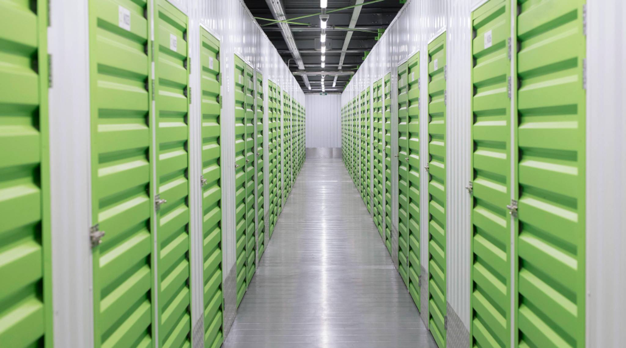 A long row of green storage units on either side of a hallway