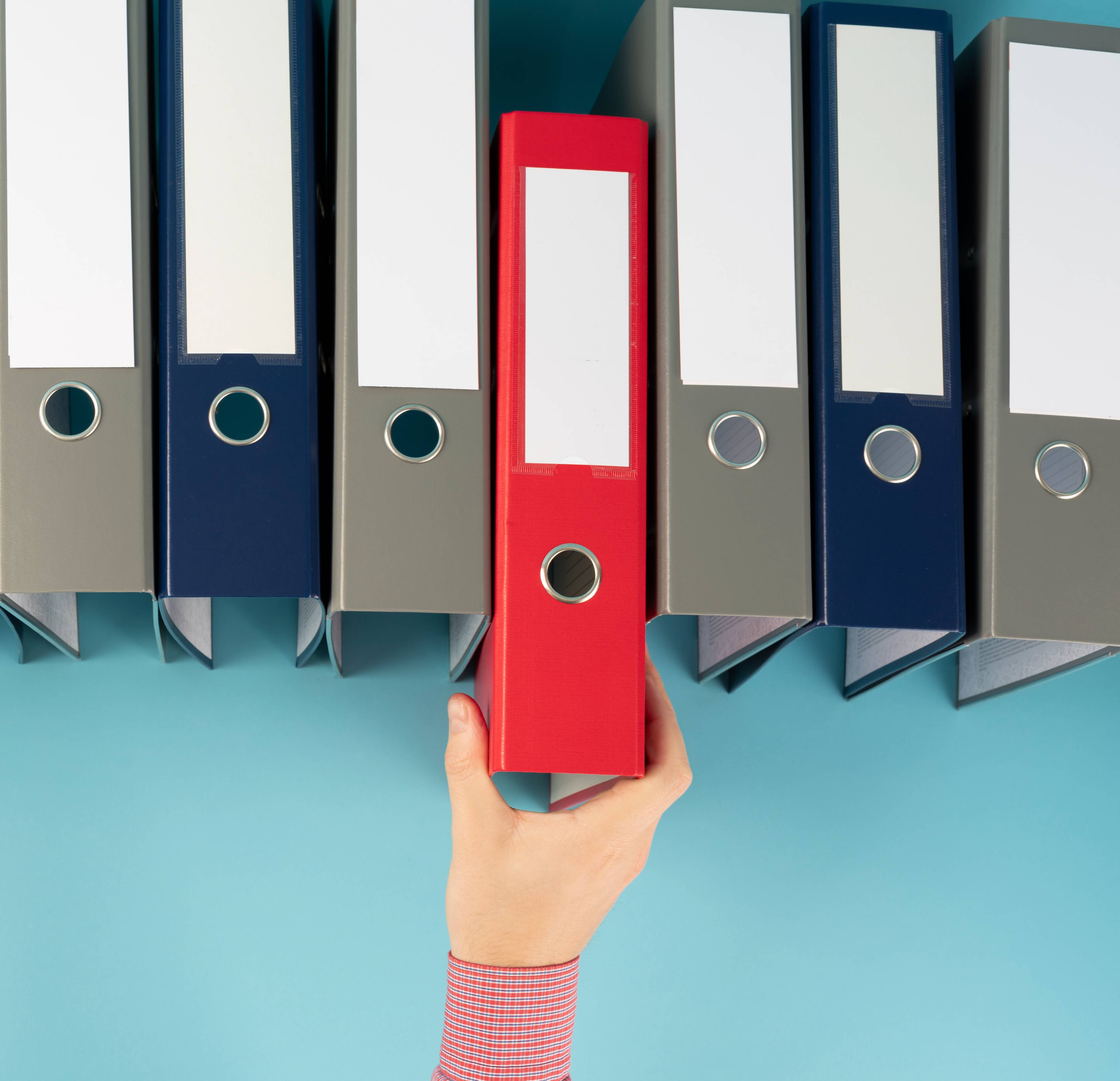 Hand reaching for ring binder used for stored documents