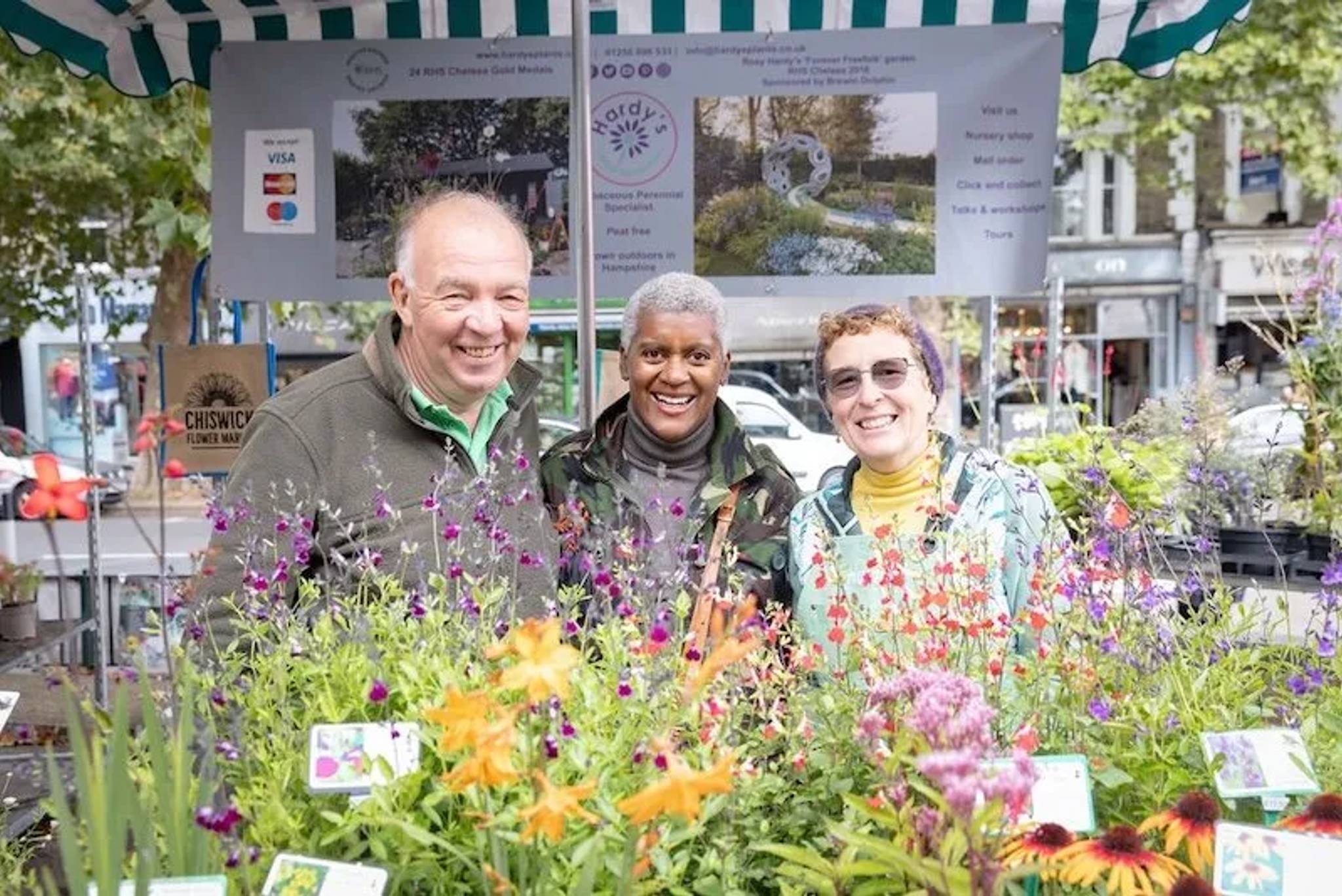 3 market traders smiling behind plants