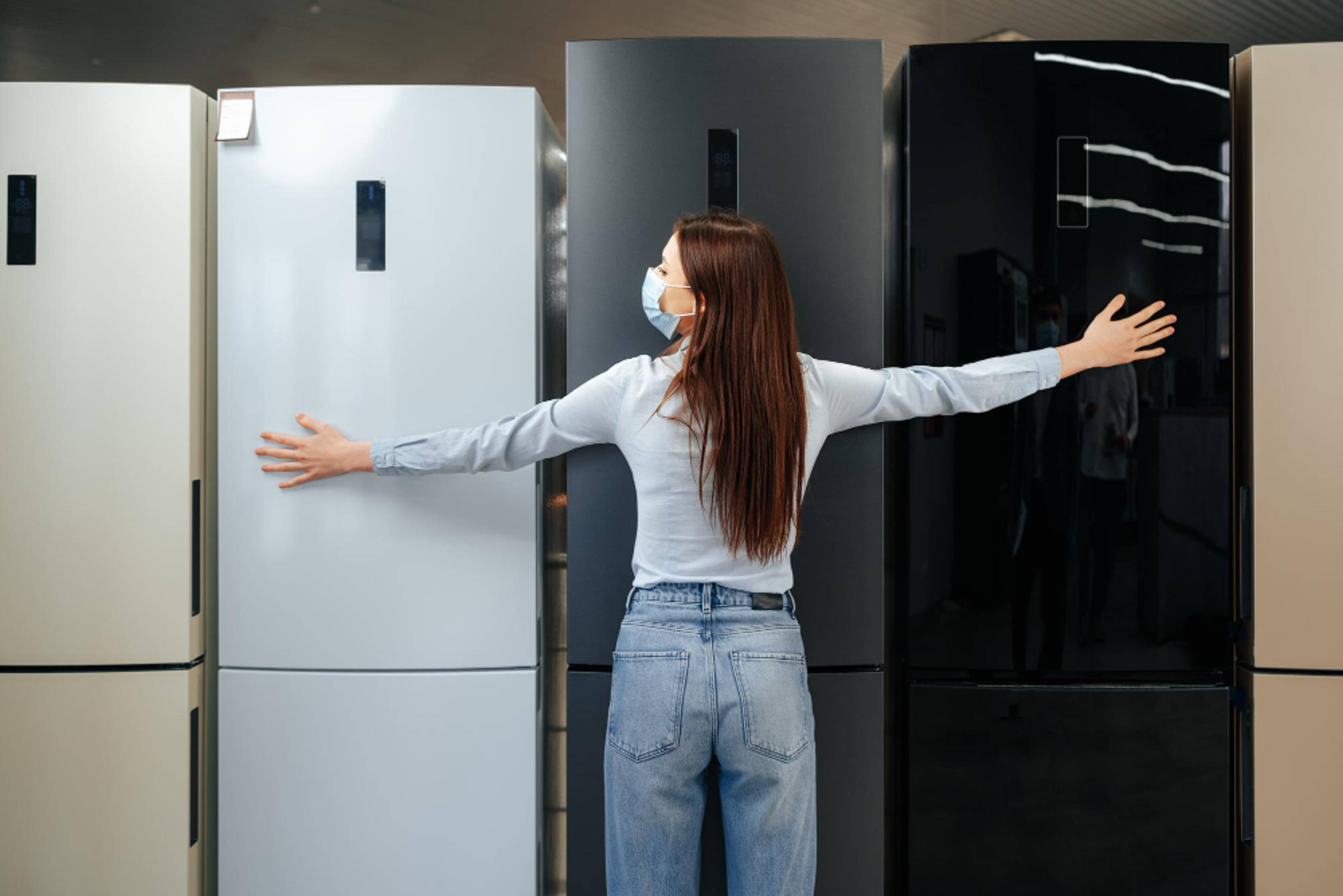 Woman with her arms stretch out in front of a row of refrigerators