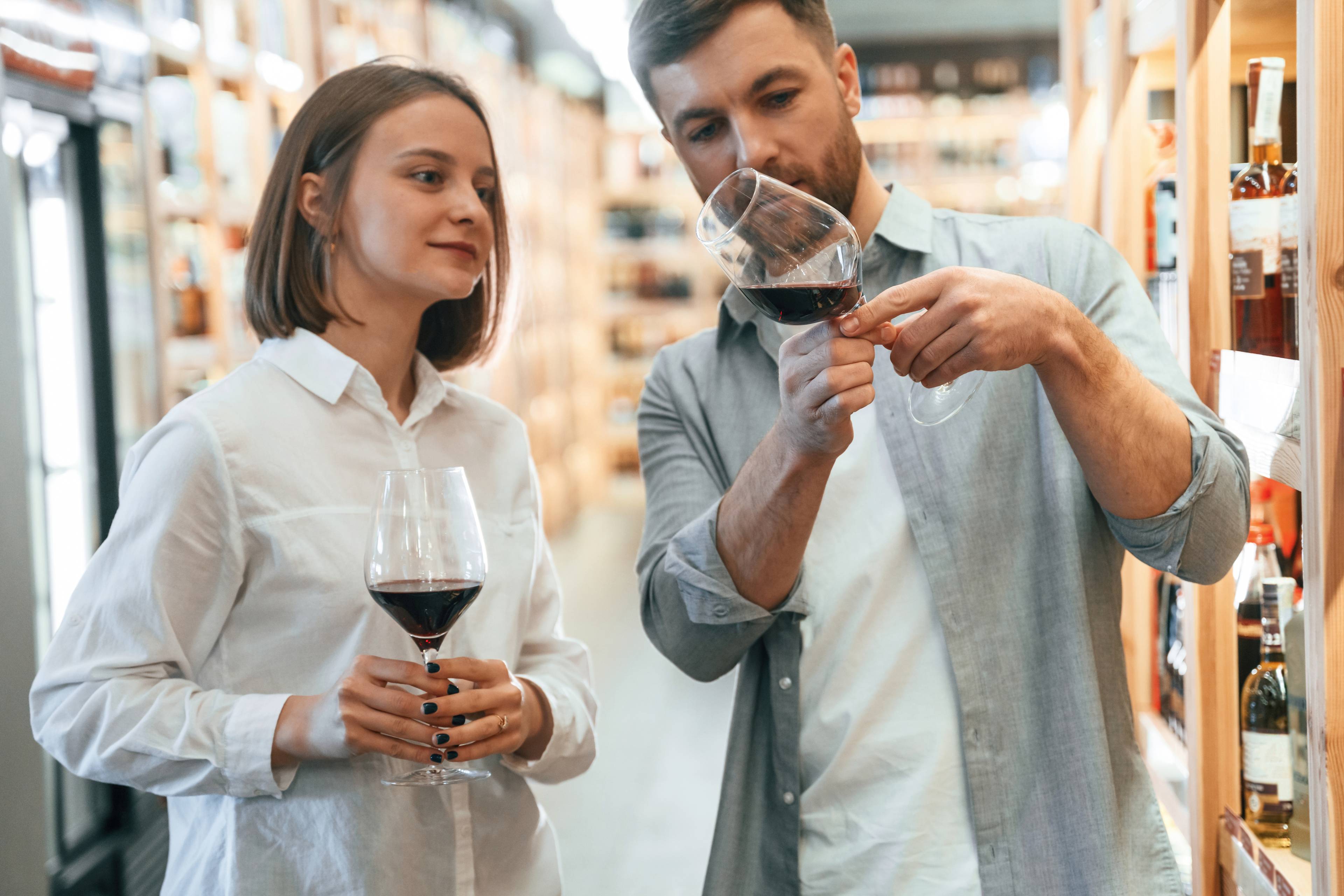 Glasses with drink Take a sample Man and woman are choosing wine in the shop