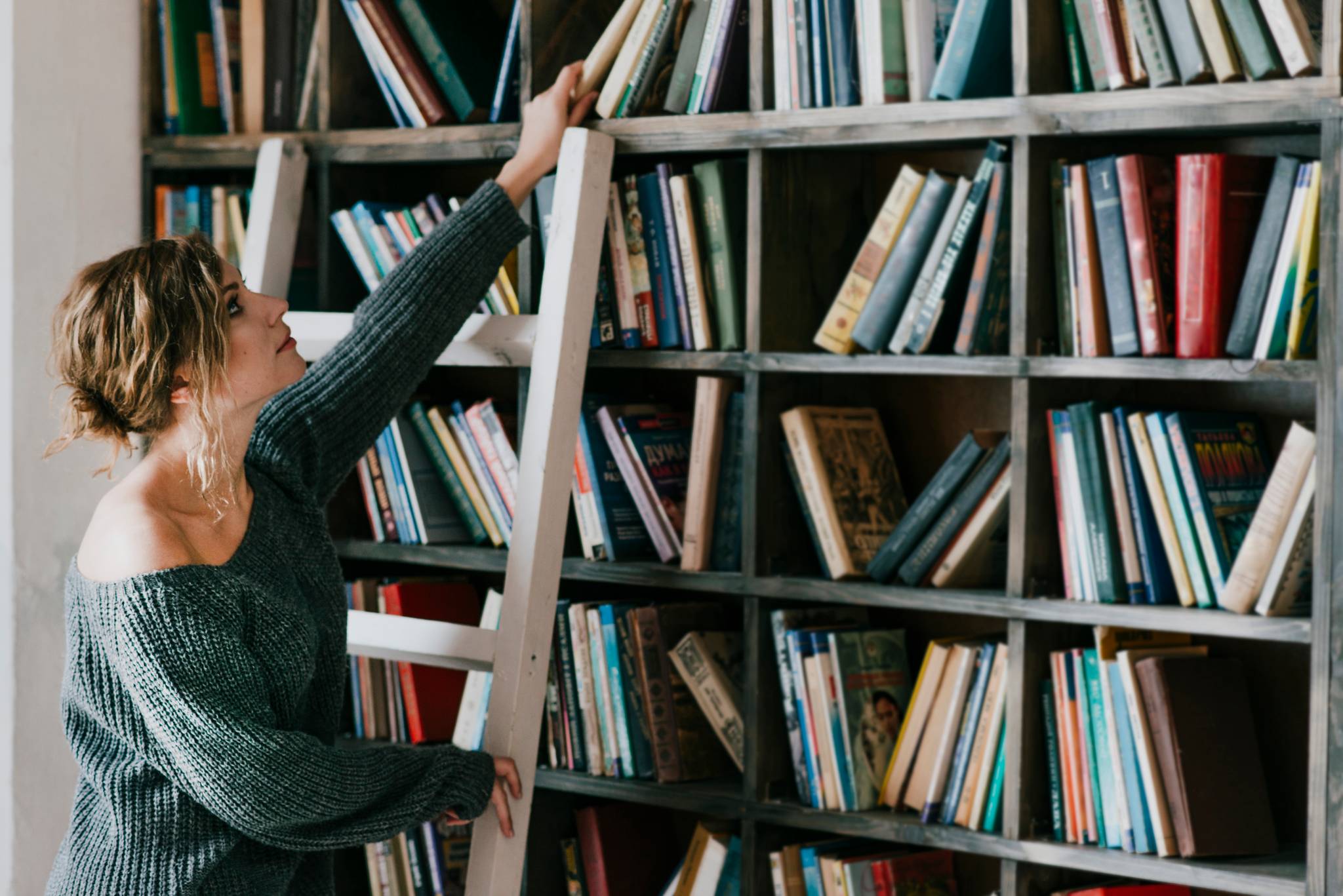 Woman on ladder on shelves with books