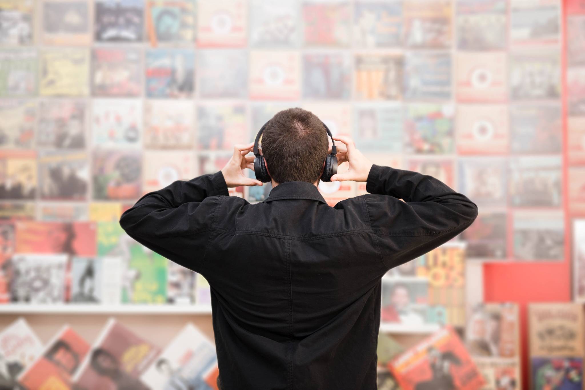 Medium shot back view of young man listening to music in store