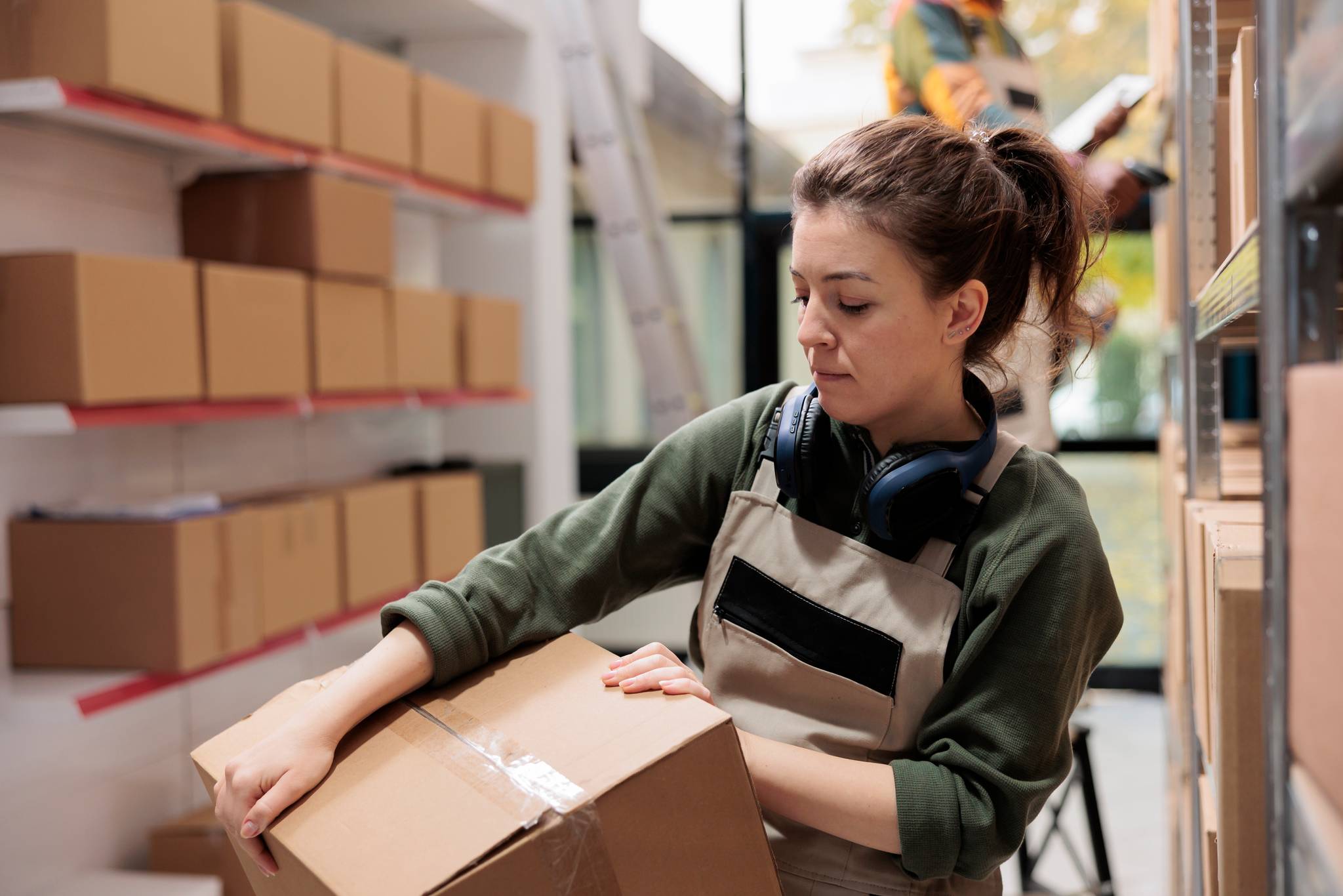 Female employee carrying box in warehouse