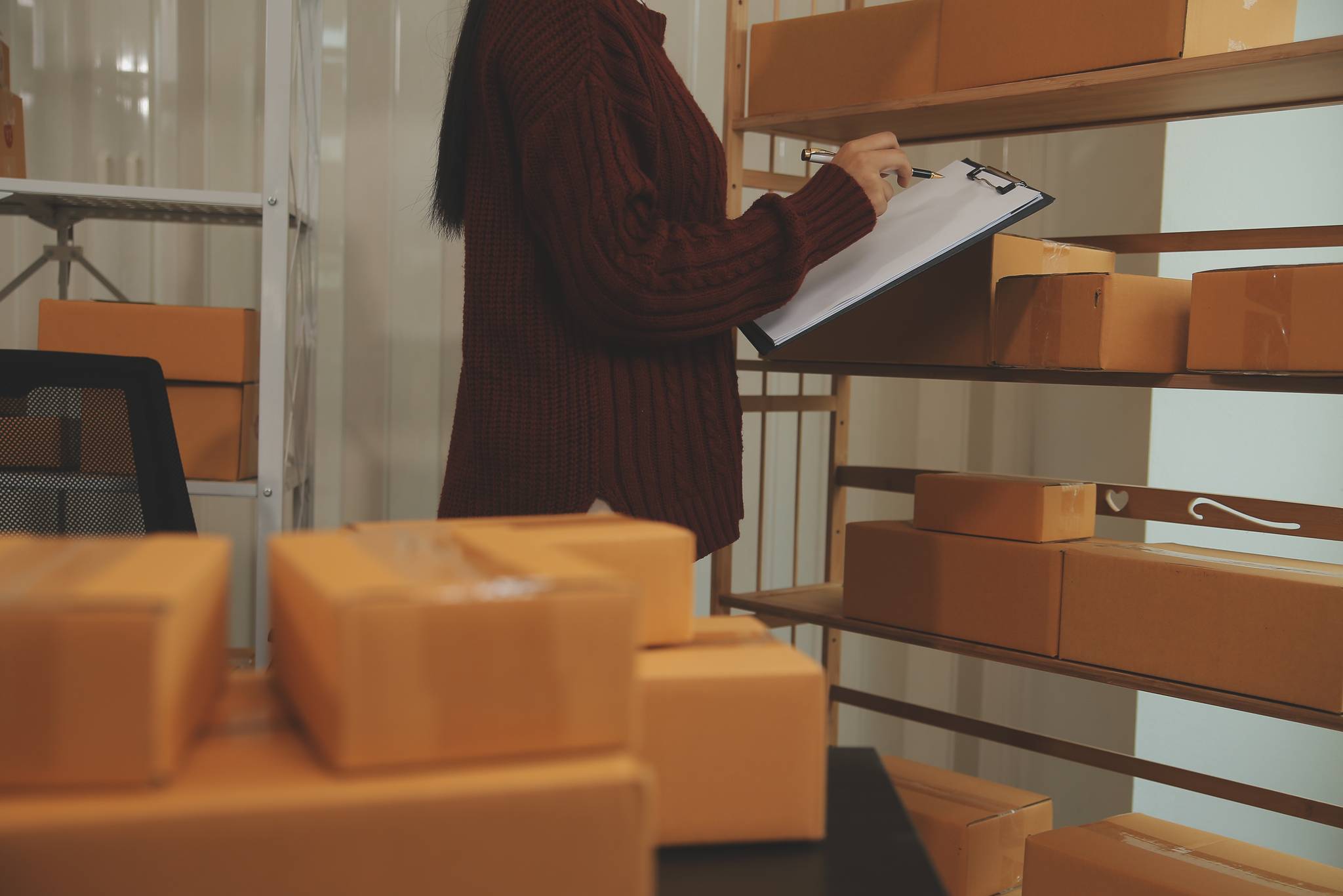 Young woman checking inventory in a small storage unit.