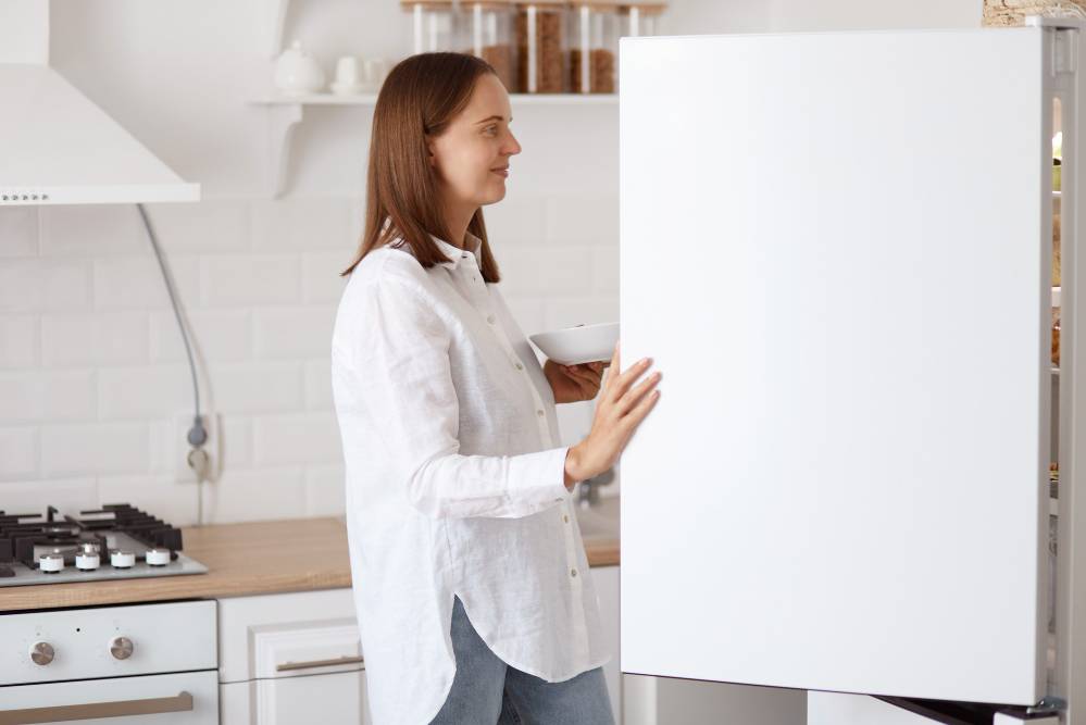 Woman smiling as she looks into her fridge