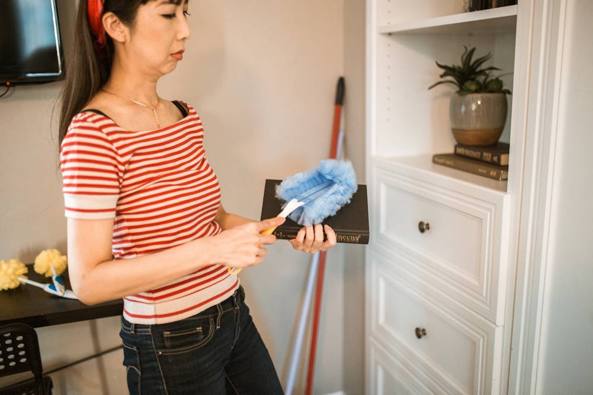 Woman at home dusting a book to keep it clean