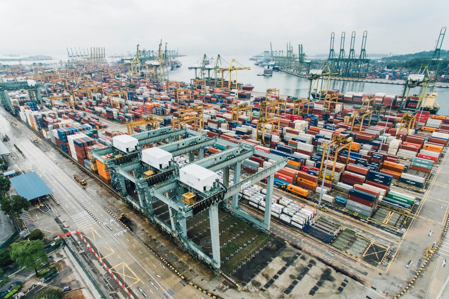 Aerial view of stacked shipping containers and gantry cranes at a major international container terminal.