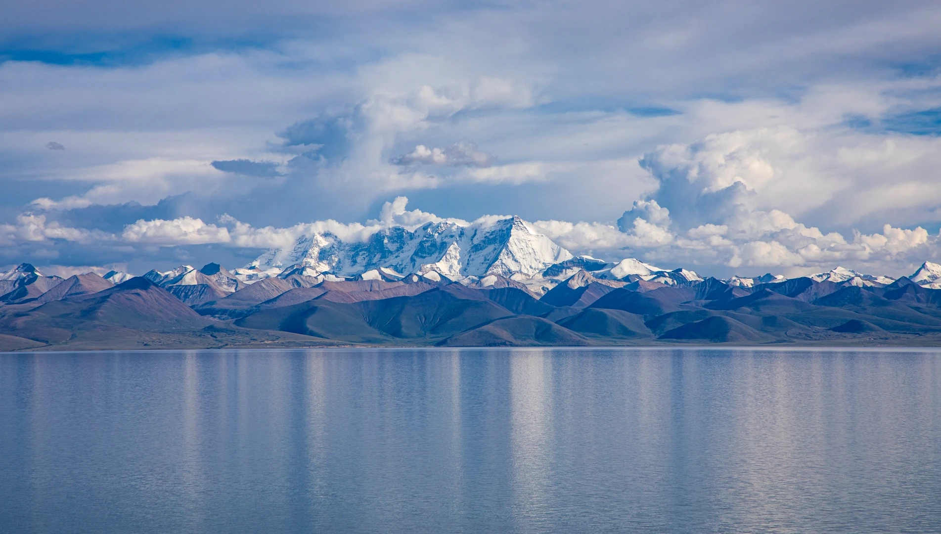Blue Namsto lake with snow capped montains in the background