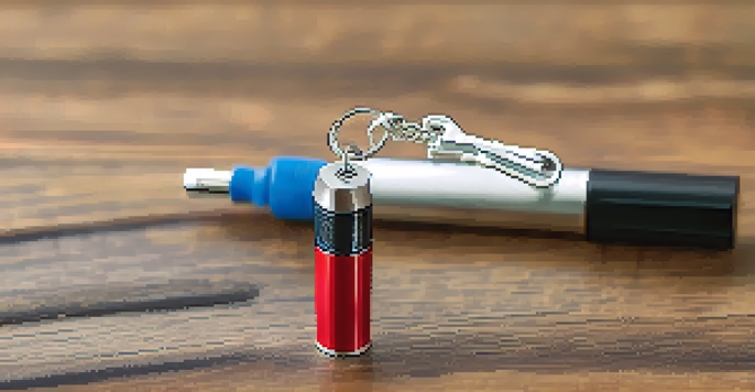 A close-up view of a self defense keychain with a tactical pen and pepper spray on a wooden surface, illuminated by soft natural light.