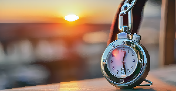 A close-up of a stylish personal alarm keychain attached to a backpack, with a vibrant sunset behind it.