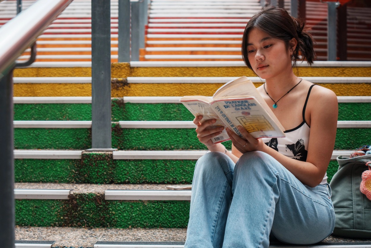 Young student reading a book on rainbow coloured stairs at Griffith South Bank.