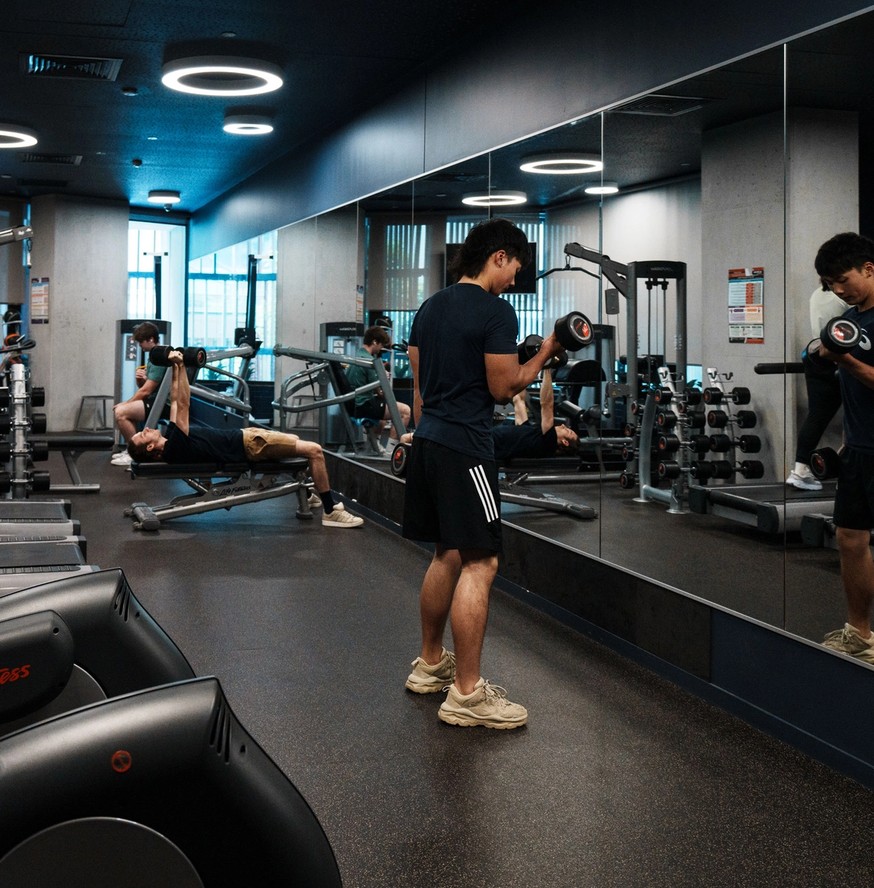 Student working out with weights in the gym