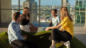 Group of students relaxing and talking on the Student One sky deck