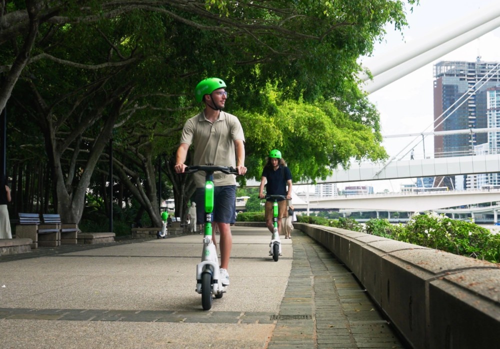 Students riding Lime scooters along the Brisbane River
