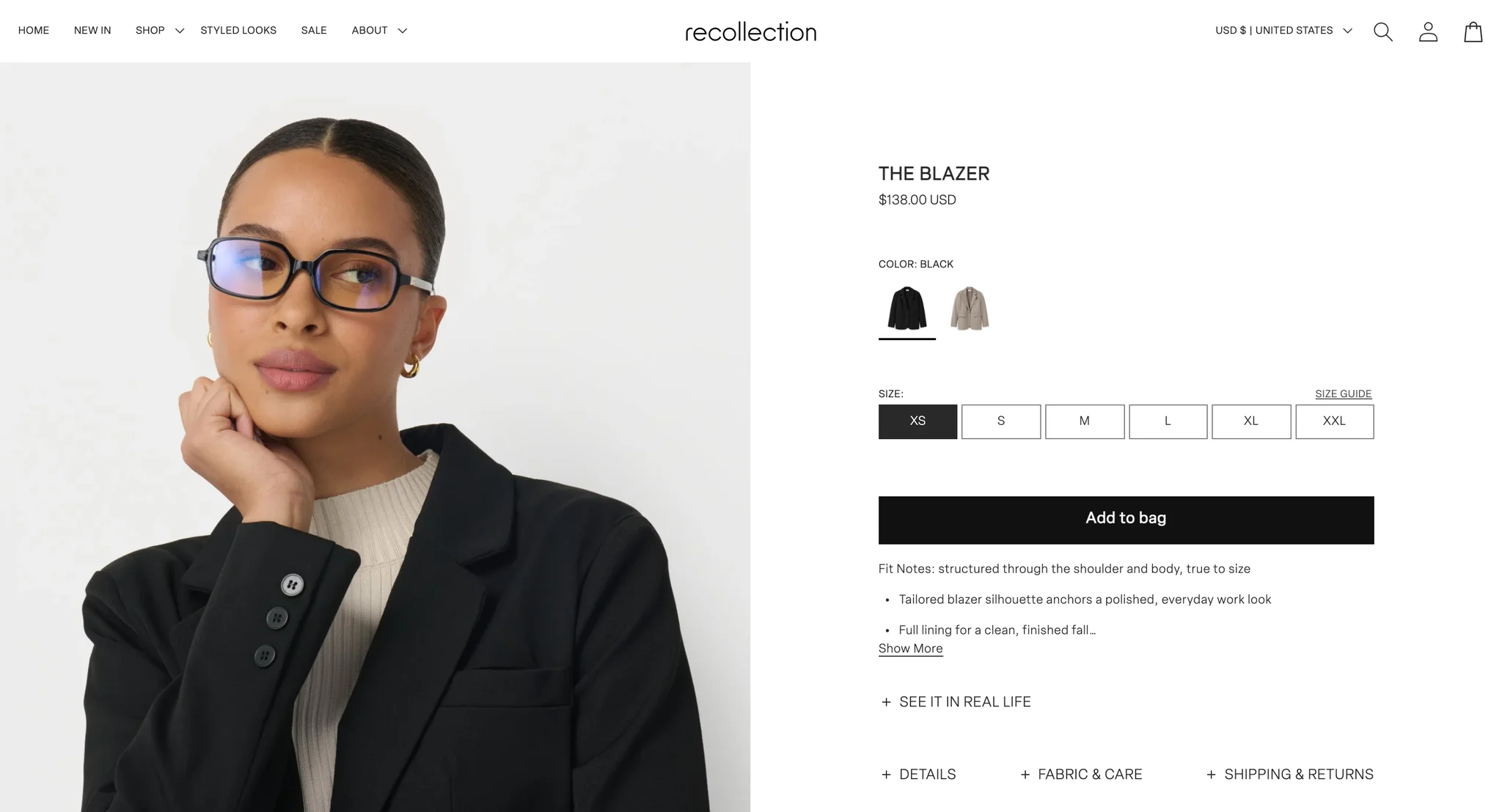 The Blazer product page: a model in black glasses and the black blazer, beside the title with the $138.00 price under it, black and taupe image swatches, sizes XS to XXL with a Size Guide link, a black Add to bag button, a "See it in real life" toggle and the Details, Fabric & Care and Shipping & Returns tabs
