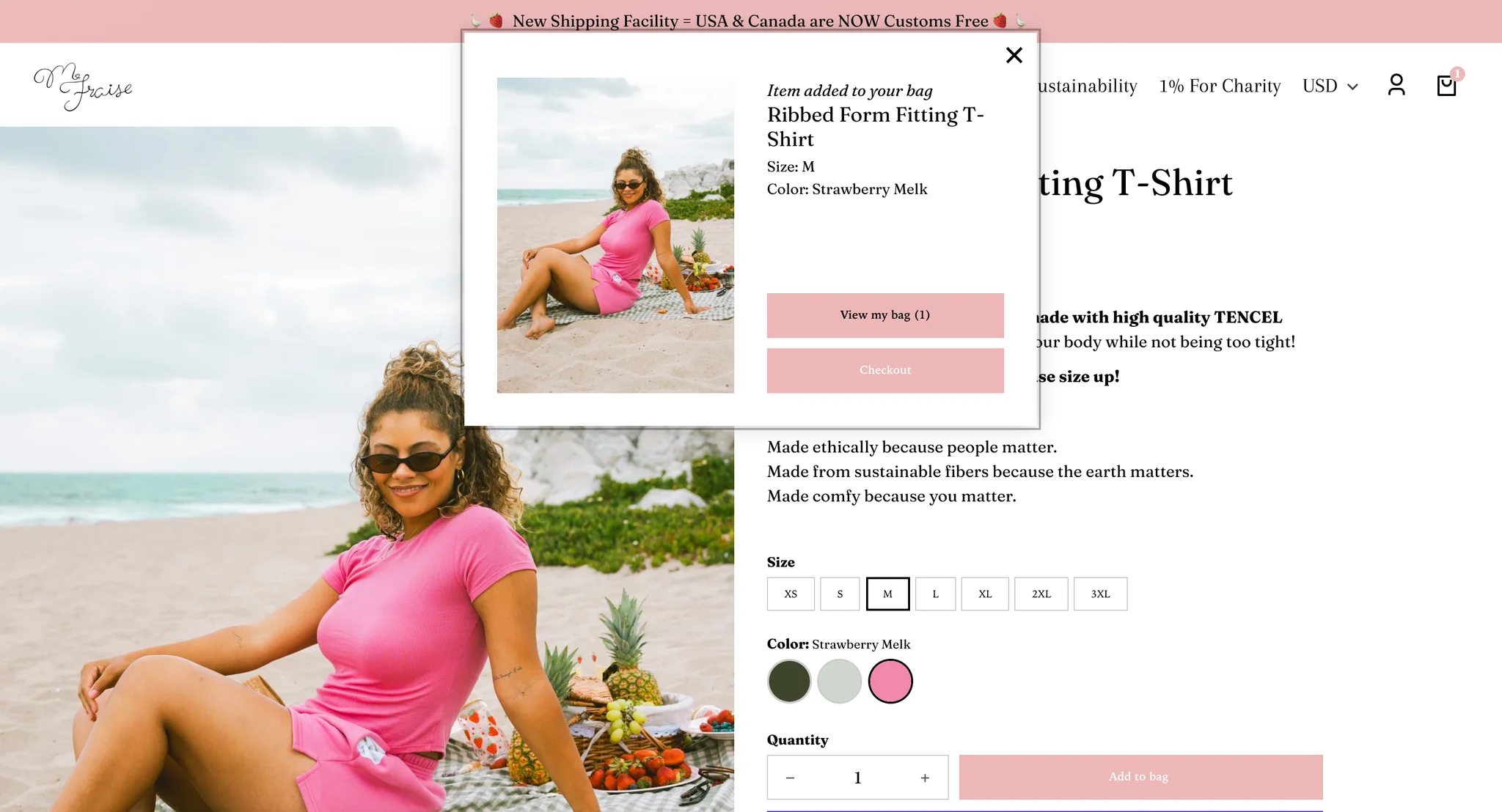 "Item added to your bag" pop-up for the Ribbed Form Fitting T-Shirt in size M and Strawberry Melk, with View my bag and Checkout buttons, over the product page now showing the pink tee at a beach picnic