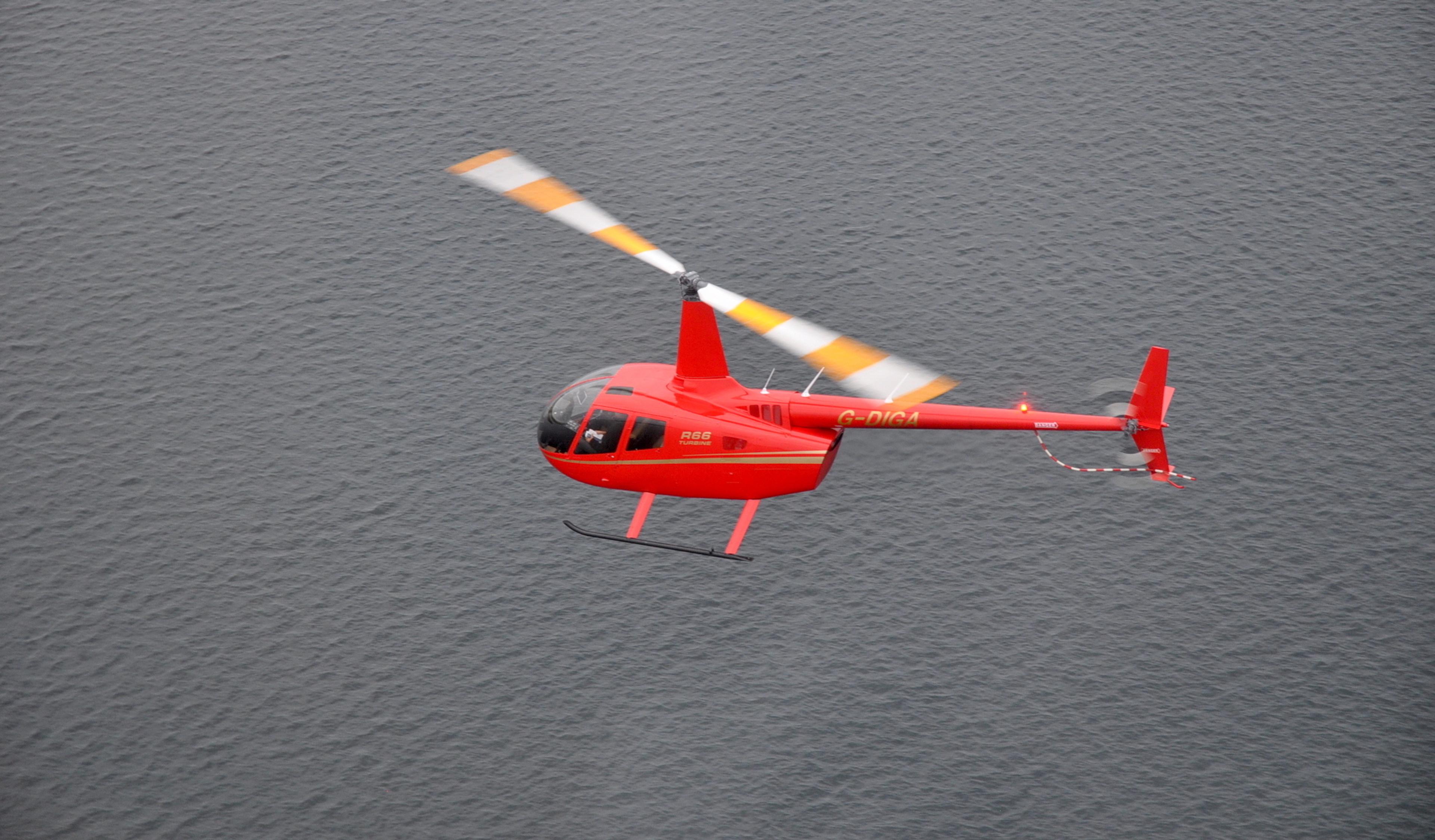Red Robinson helicopter flying over water