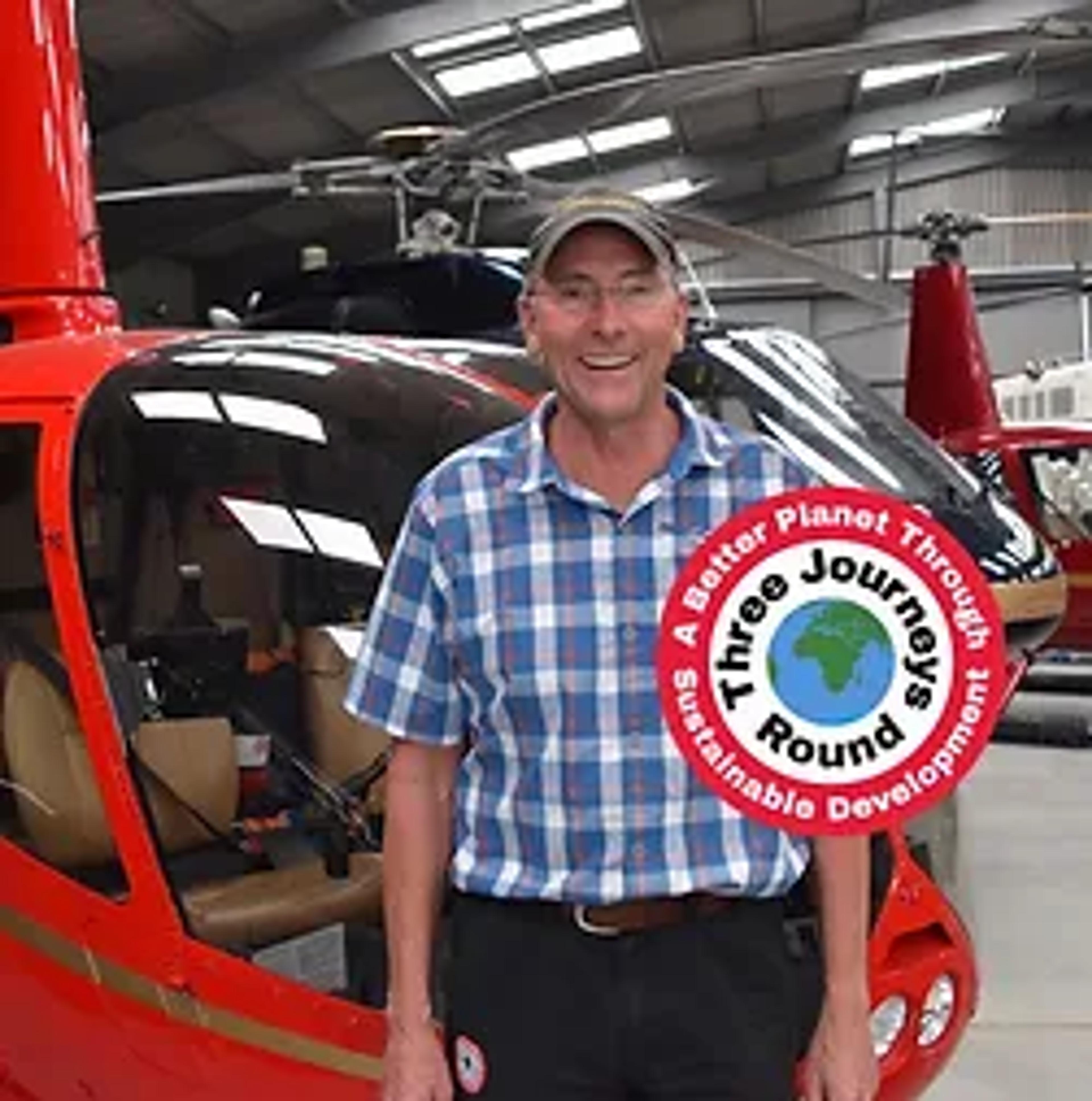 Captain Peter Wilson in front of a red helicopter in the hangar