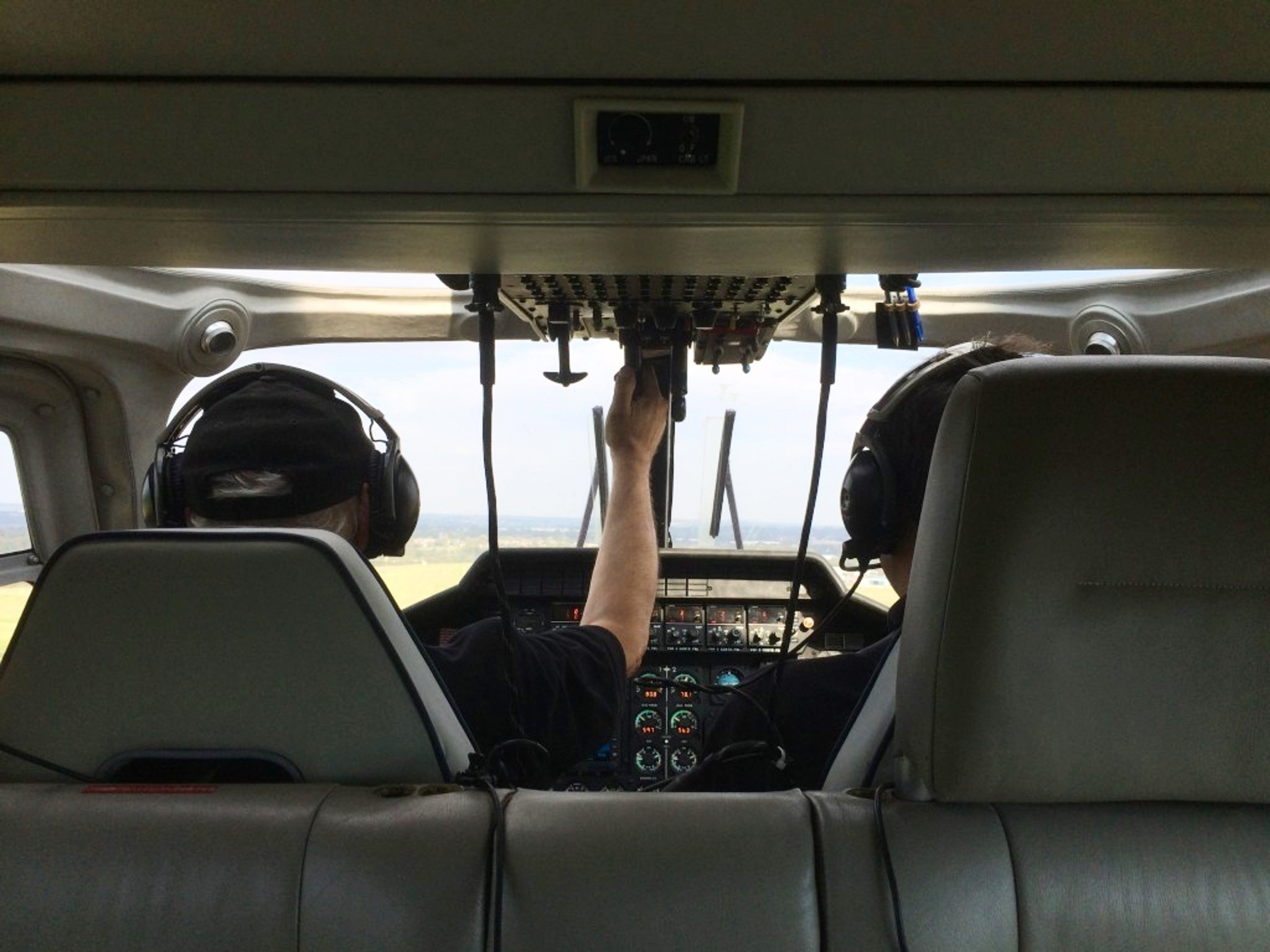 View from the back seat of a helicopter cockpit with two pilots