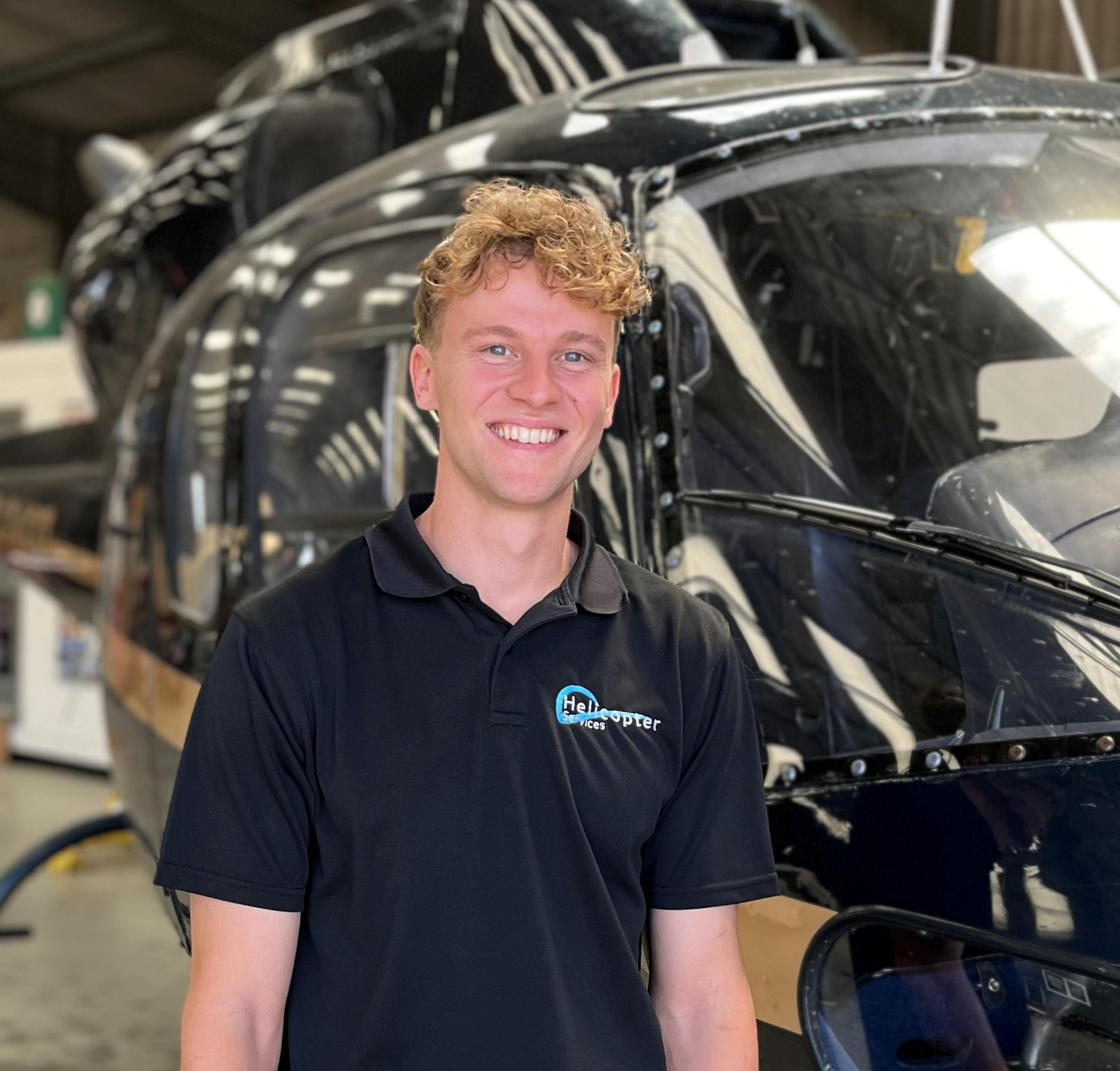 Alex Barrett standing beside a helicopter in the hangar