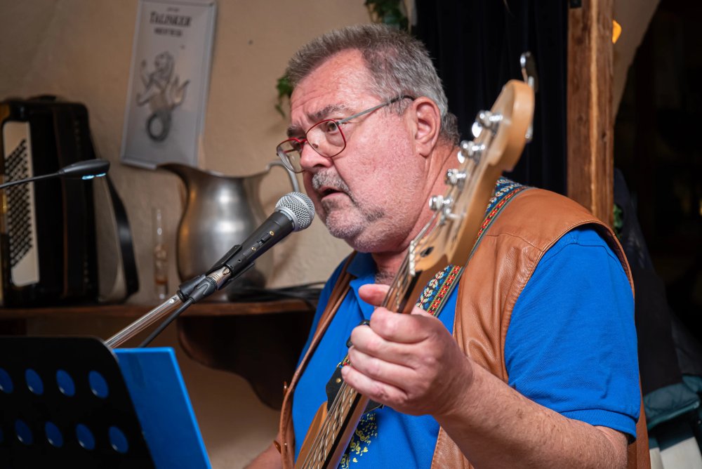 Der Bassist der Original Austrobuam singt am Mikrofon und spielt Bass.
