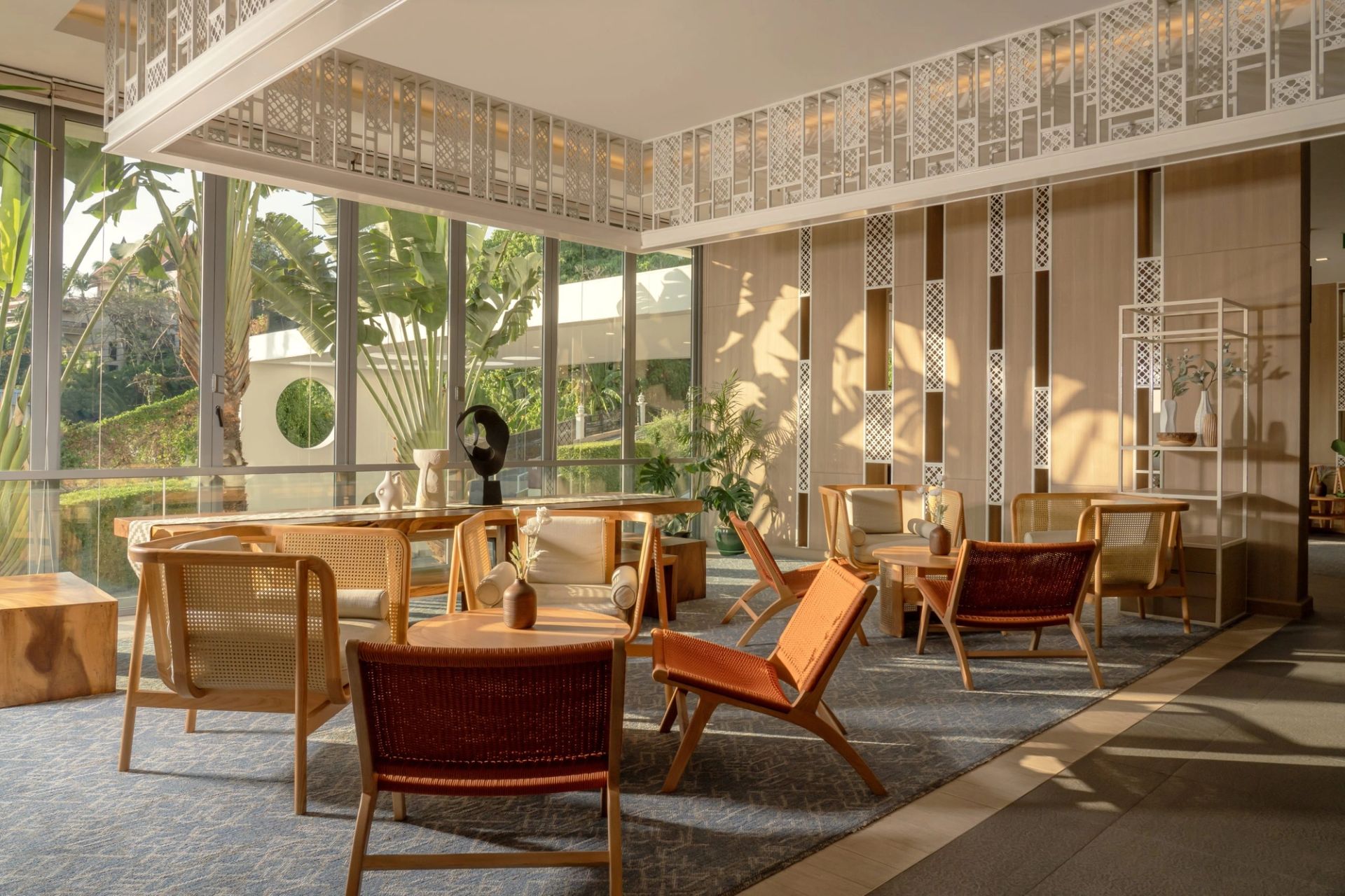 PM:AG hospitality interior — warm rattan lounge with floor-to-ceiling glass