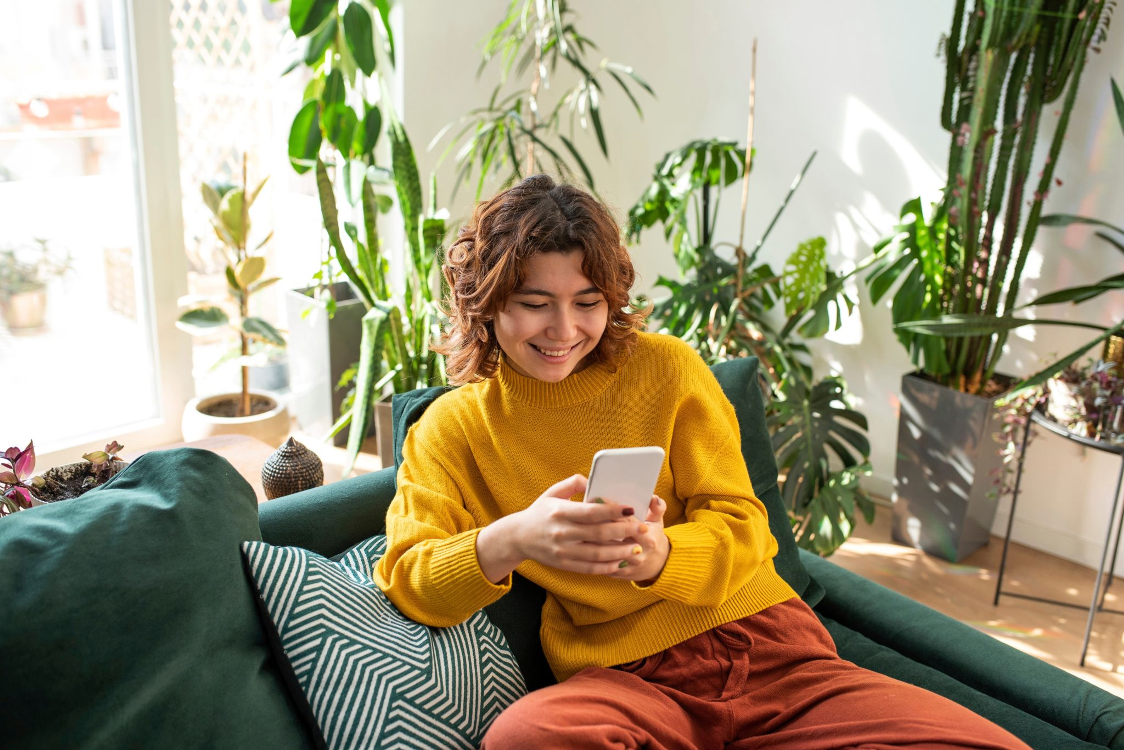 Jeune femme souriante dans un fauteuil avec son smartphone en main