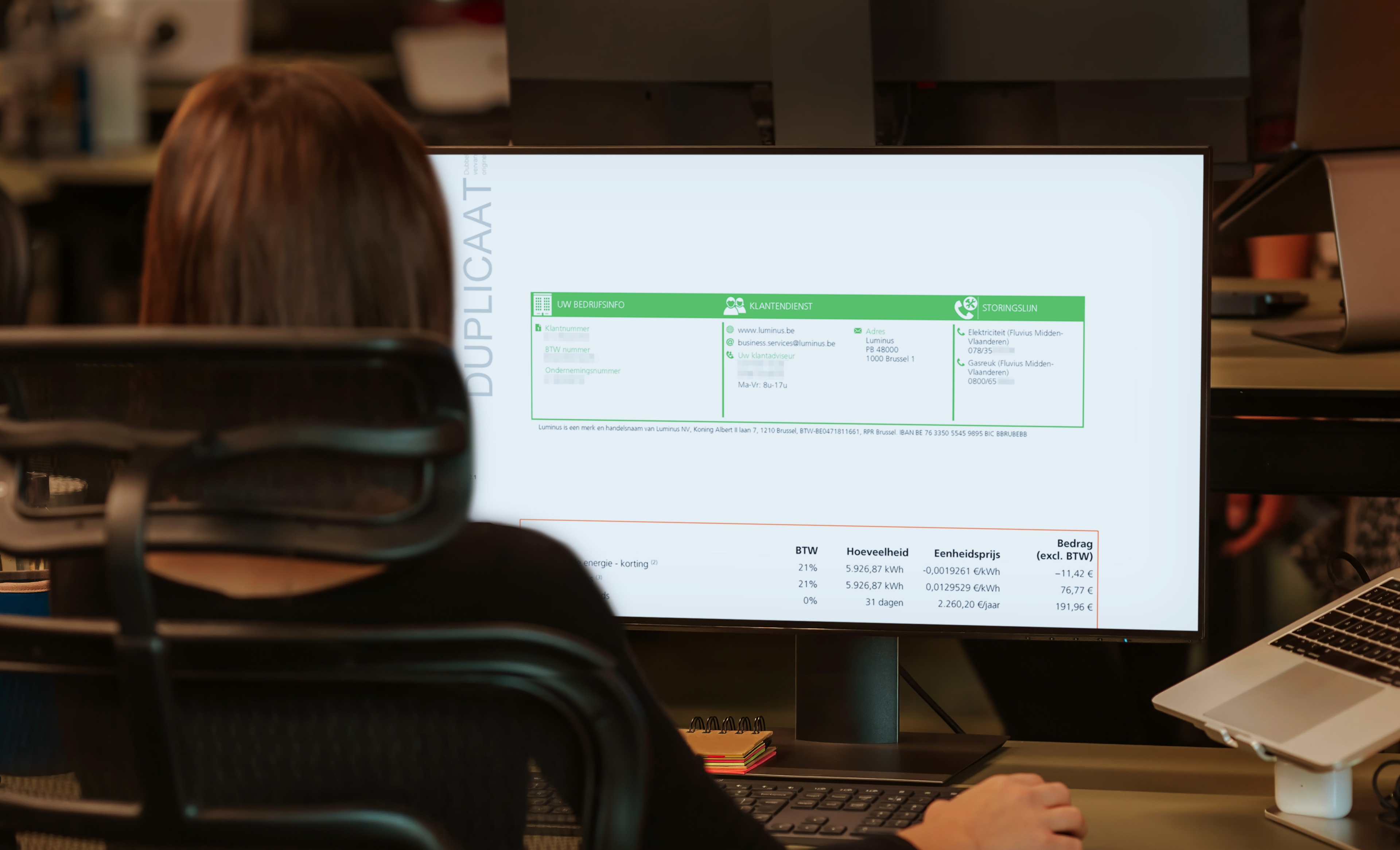 Personne travaillant sur un ordinateur affichant une facture numérique à l'écran dans un environnement de bureau