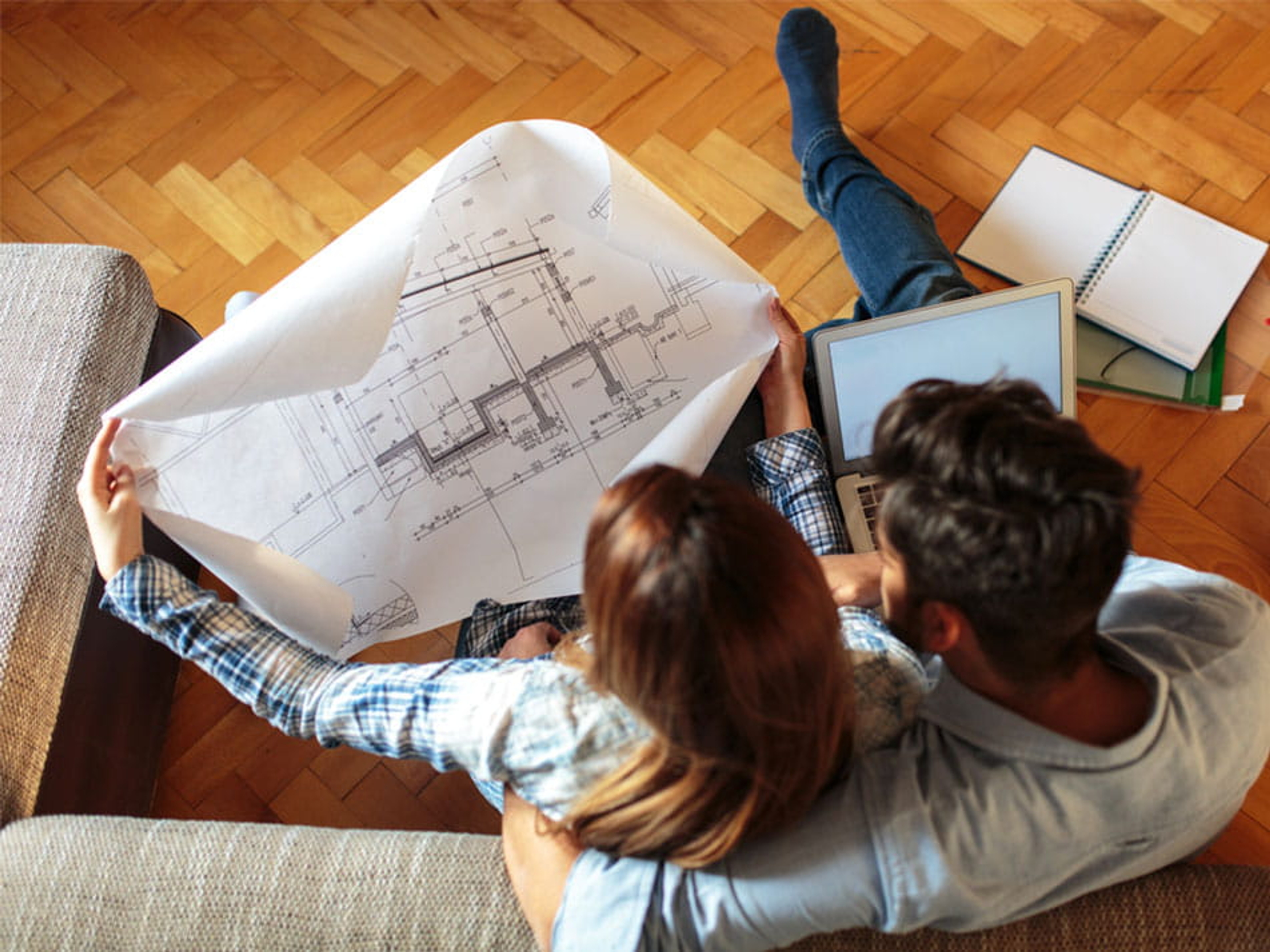 Koppel van boven gezien, zit in zetel met papieren architectenplan van hun huis .