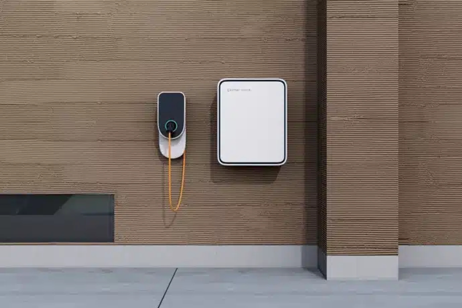 Batterie domestique murale installée à l’extérieur, associée à une borne de recharge pour voiture électrique, avec câble branché, sur une façade en bois.