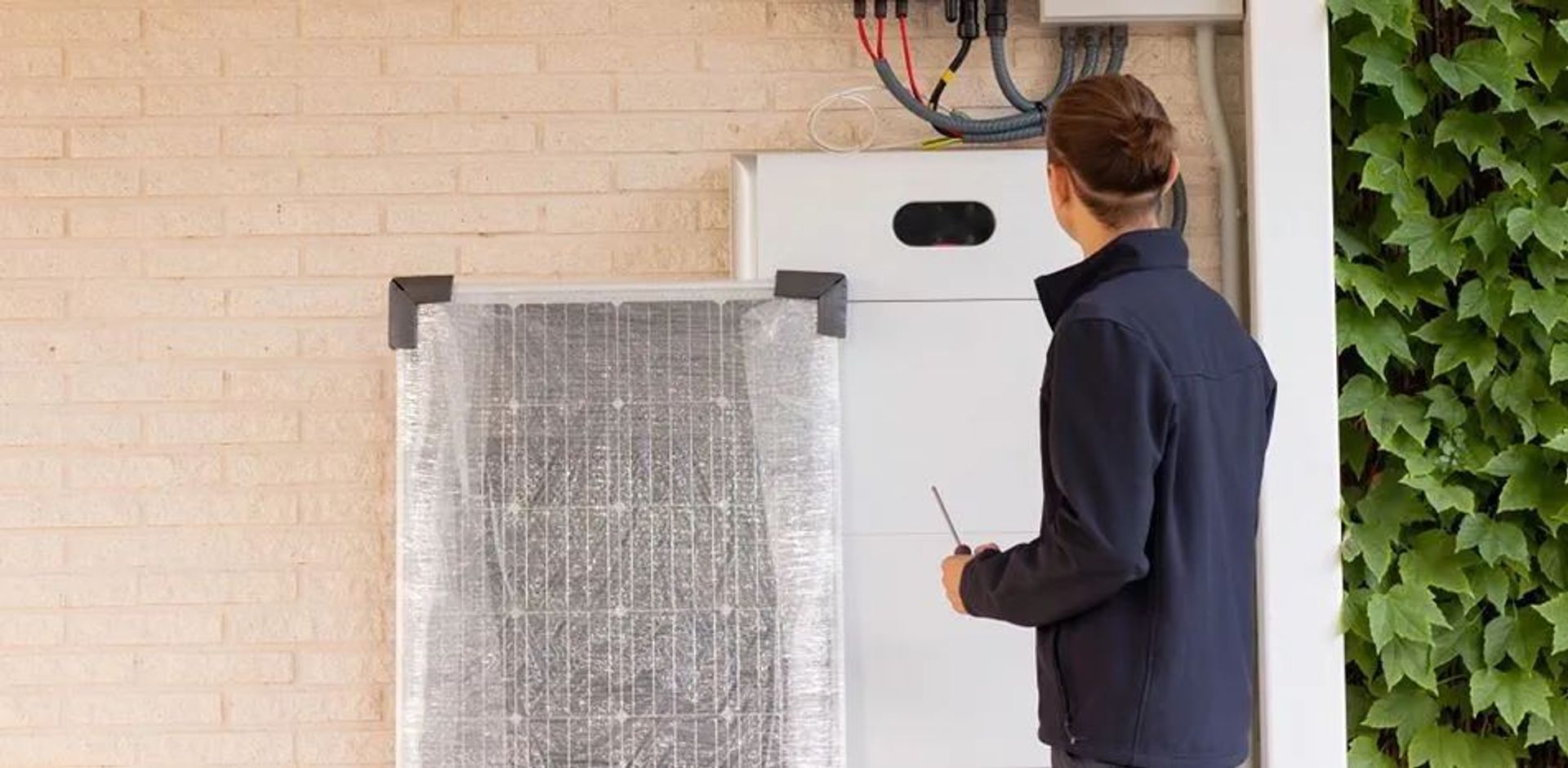 Man gezien op de rug bekijkt zijn nieuwe thuisbatterij in de garage, aangekocht via Luminus
