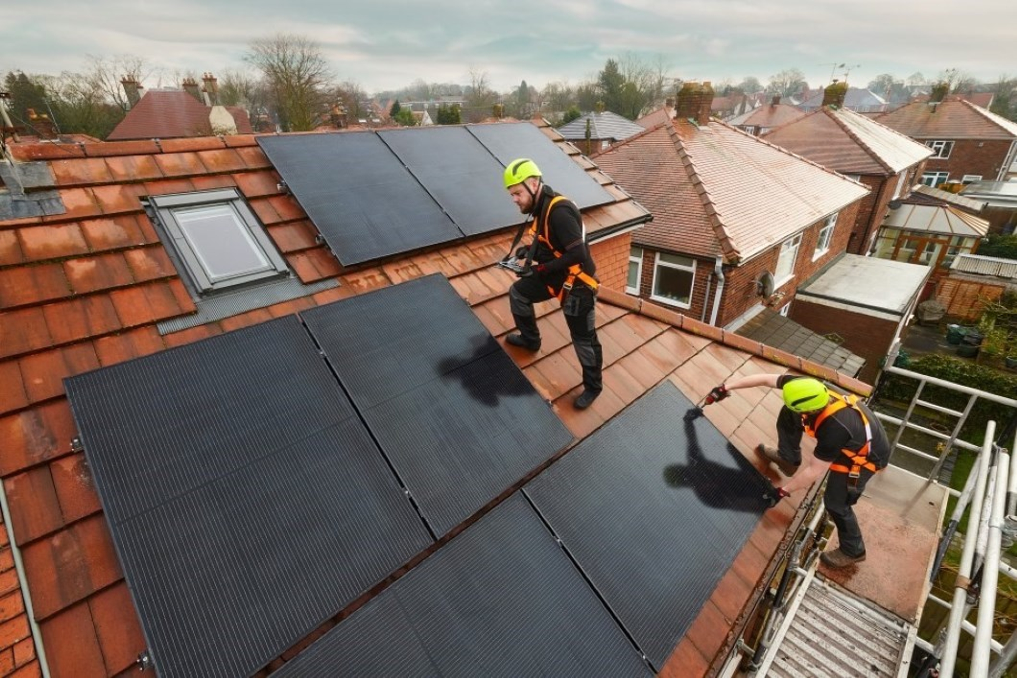 2 techniekers met gele helm op dak van een huis met zonnepanelen.