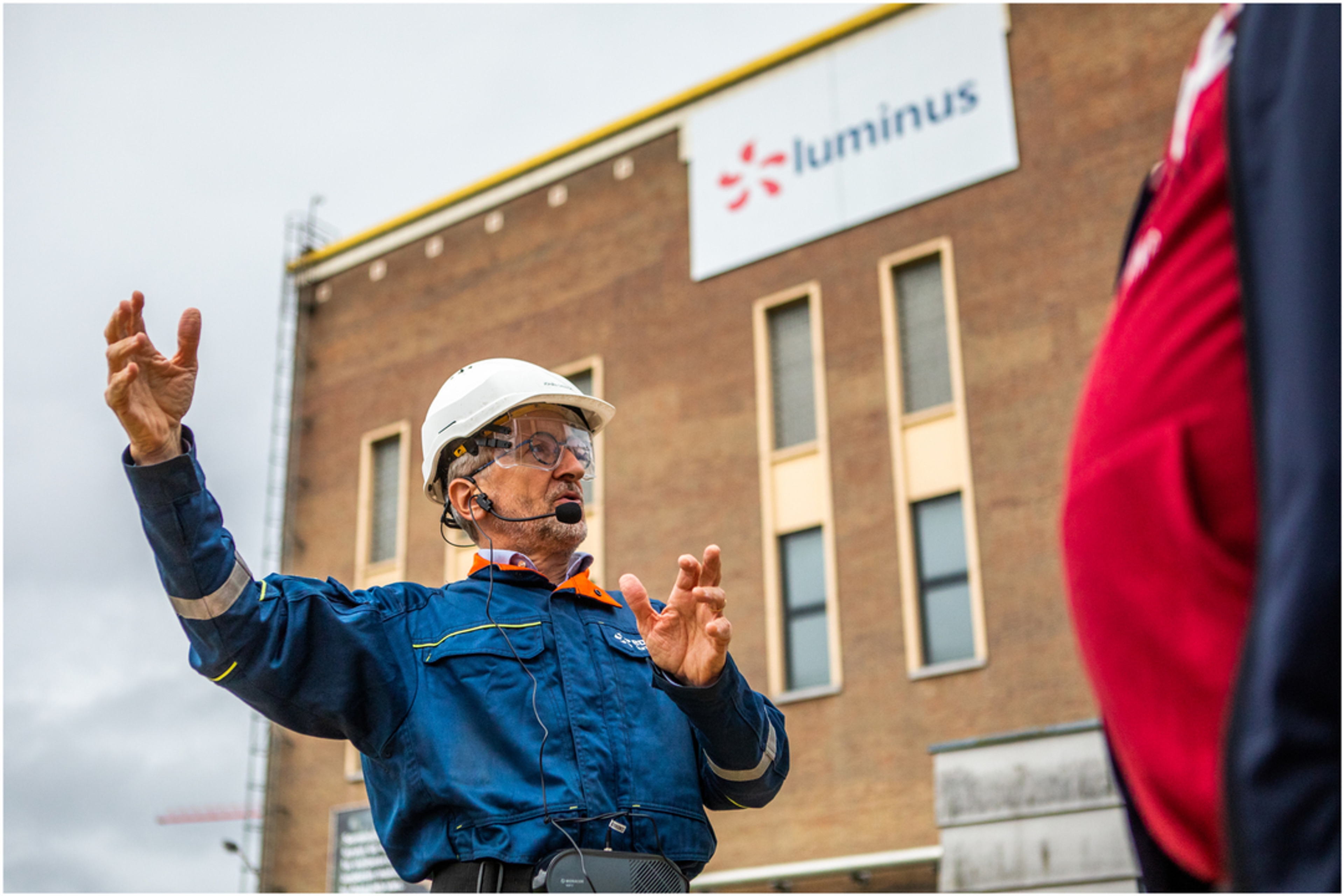 Medewerker gascentrale met ham presenteert voor Luminus gebouw