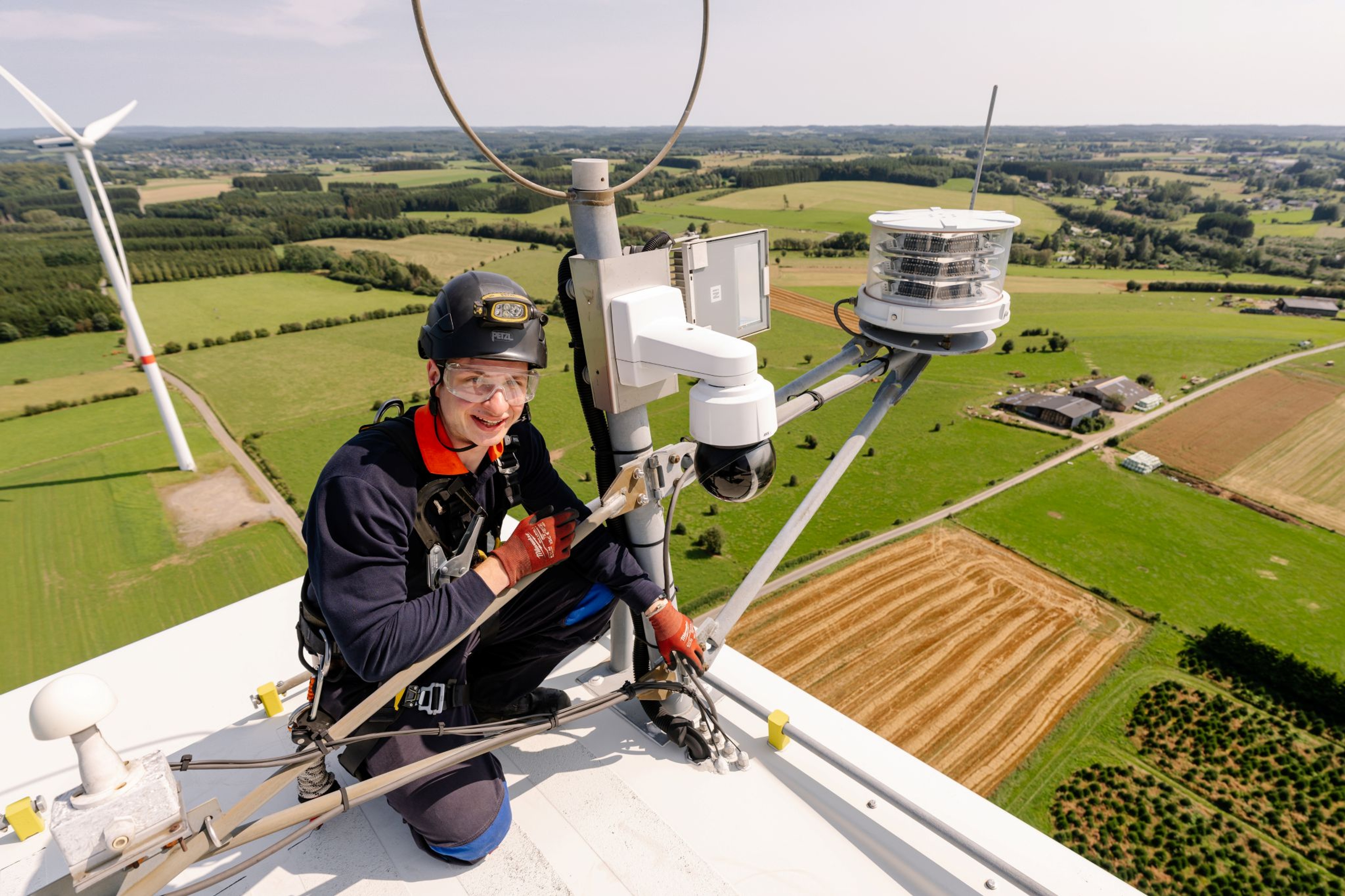 Close-up van een windturbine en een technieker op grote hoogte.