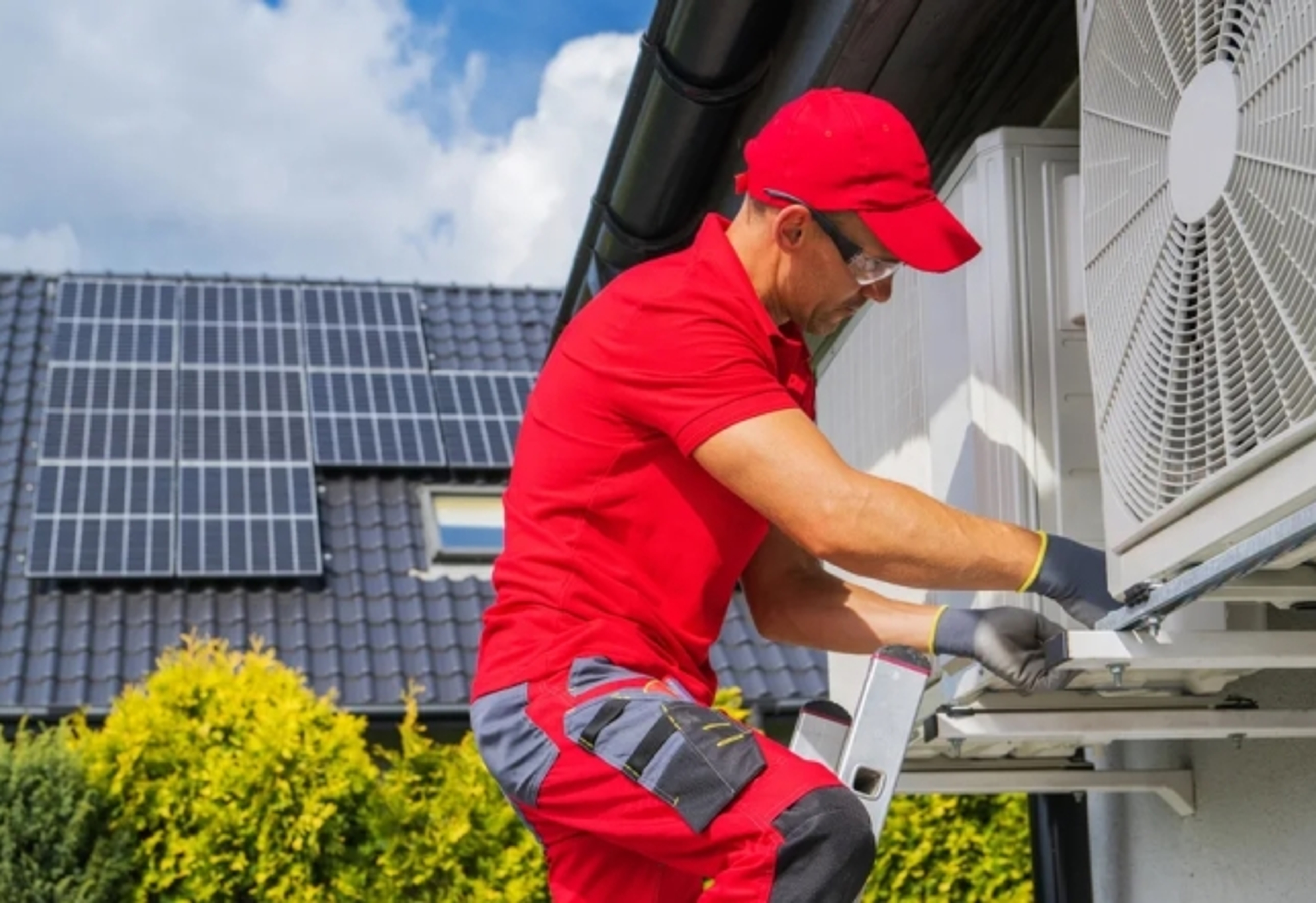 Technicien installant une pompe à chaleur à l'extérieur d'une maison avec des panneaux solaires