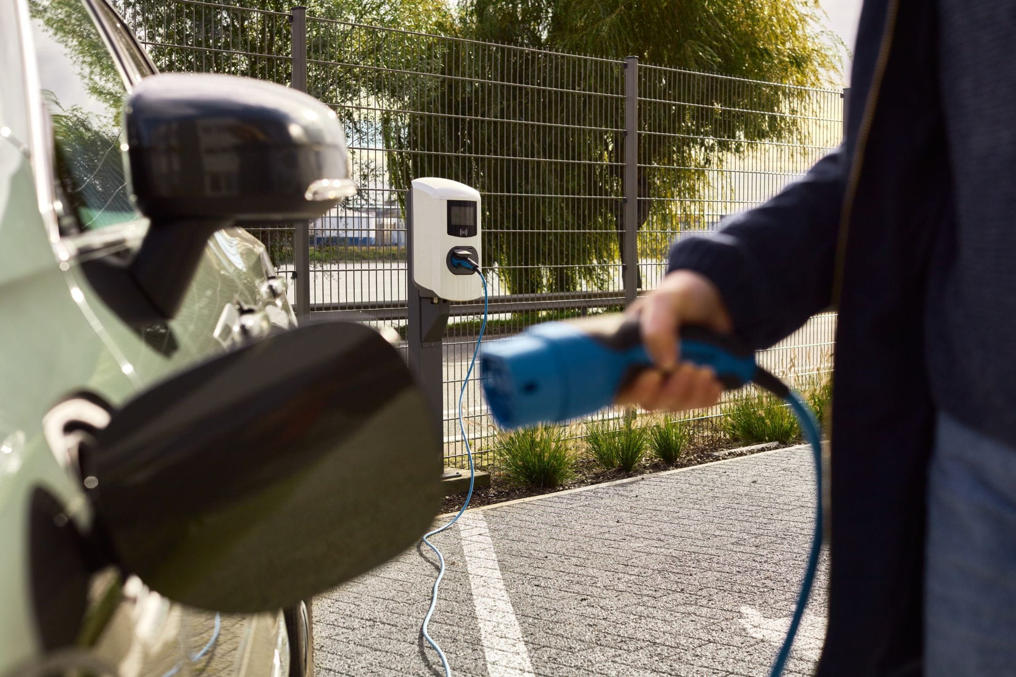 Man steekt de stekker in zijn elektrische wagen.