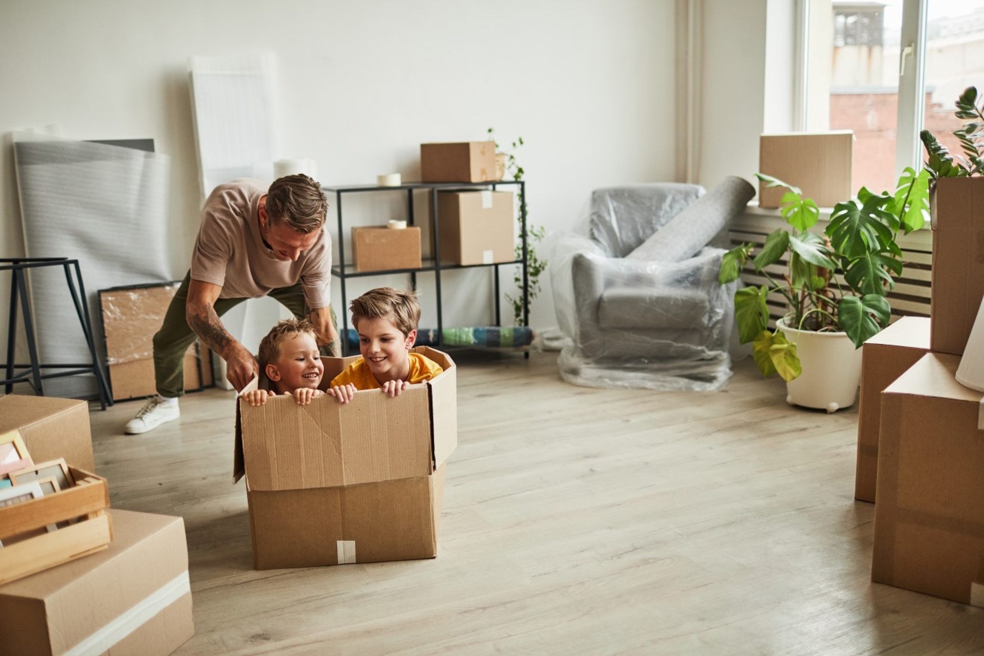 Man tussen verhuisdozen speelt met zijn kinderen