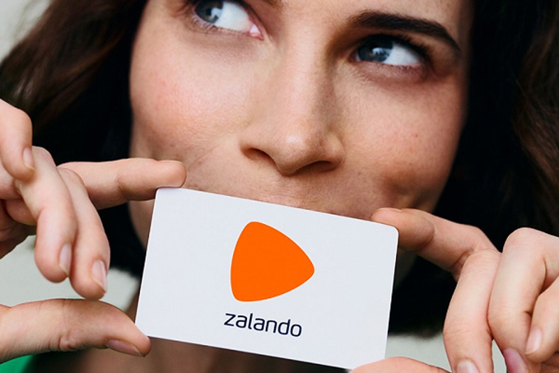 Tot 6% korting op je voucher bij Zalando, dame houdt kaartje Zalando voor de mond