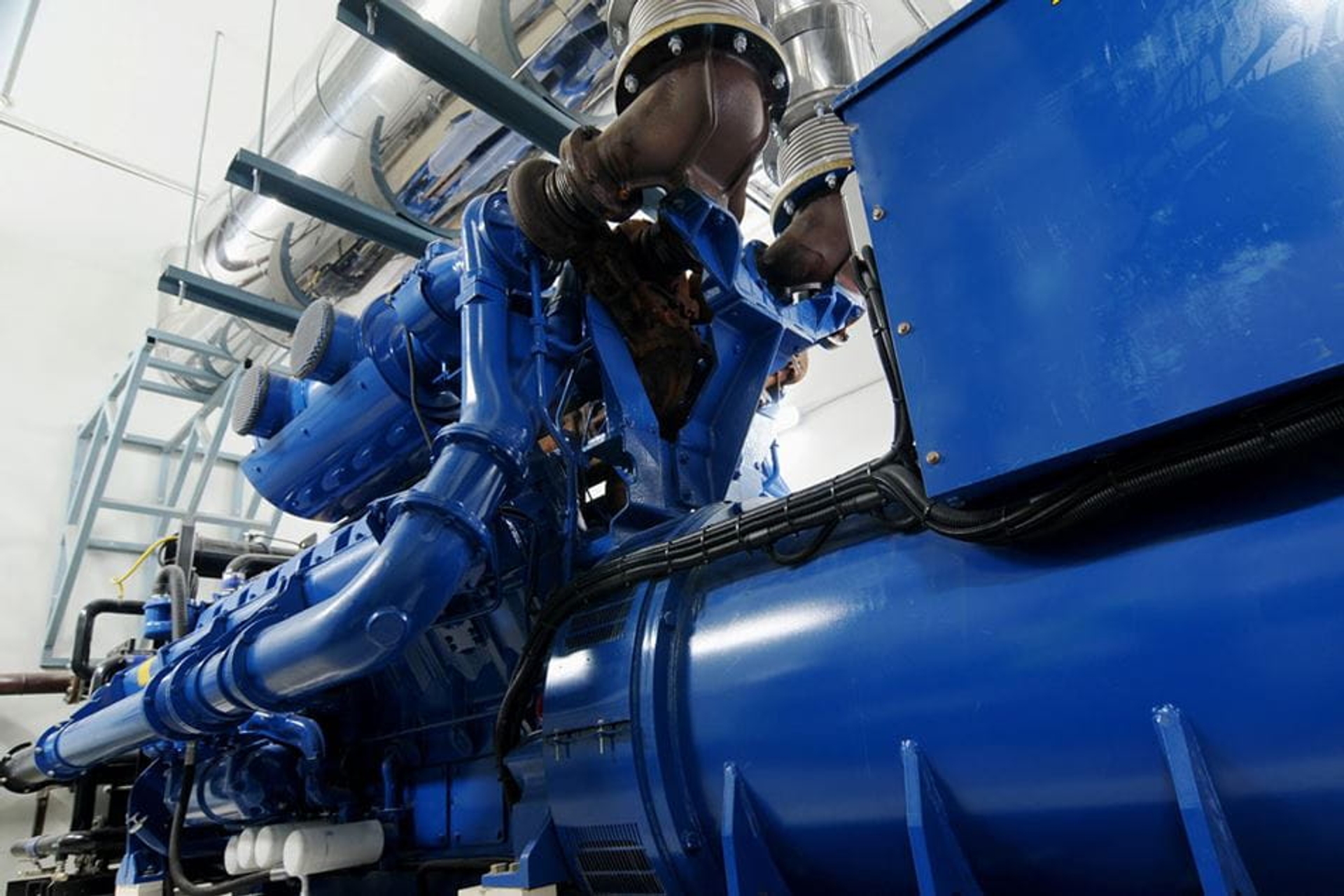 Gros plan sur une installation industrielle de cogénération avec un moteur et des tuyaux bleus