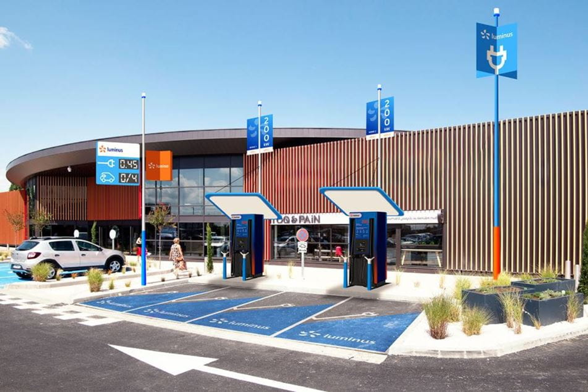 Quatre places de parking bleues dédiées à la recharge rapide devant un magasin moderne