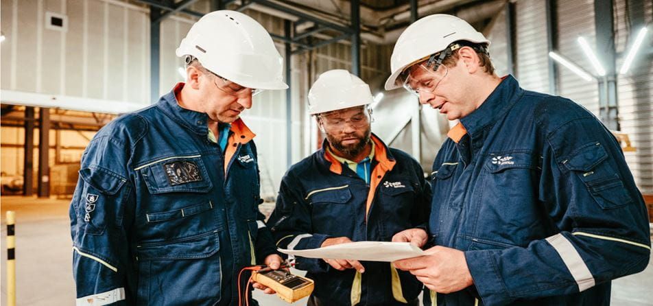 Twee Luminus-techniekers met witte helm op bekijken iets samen in een centrale.